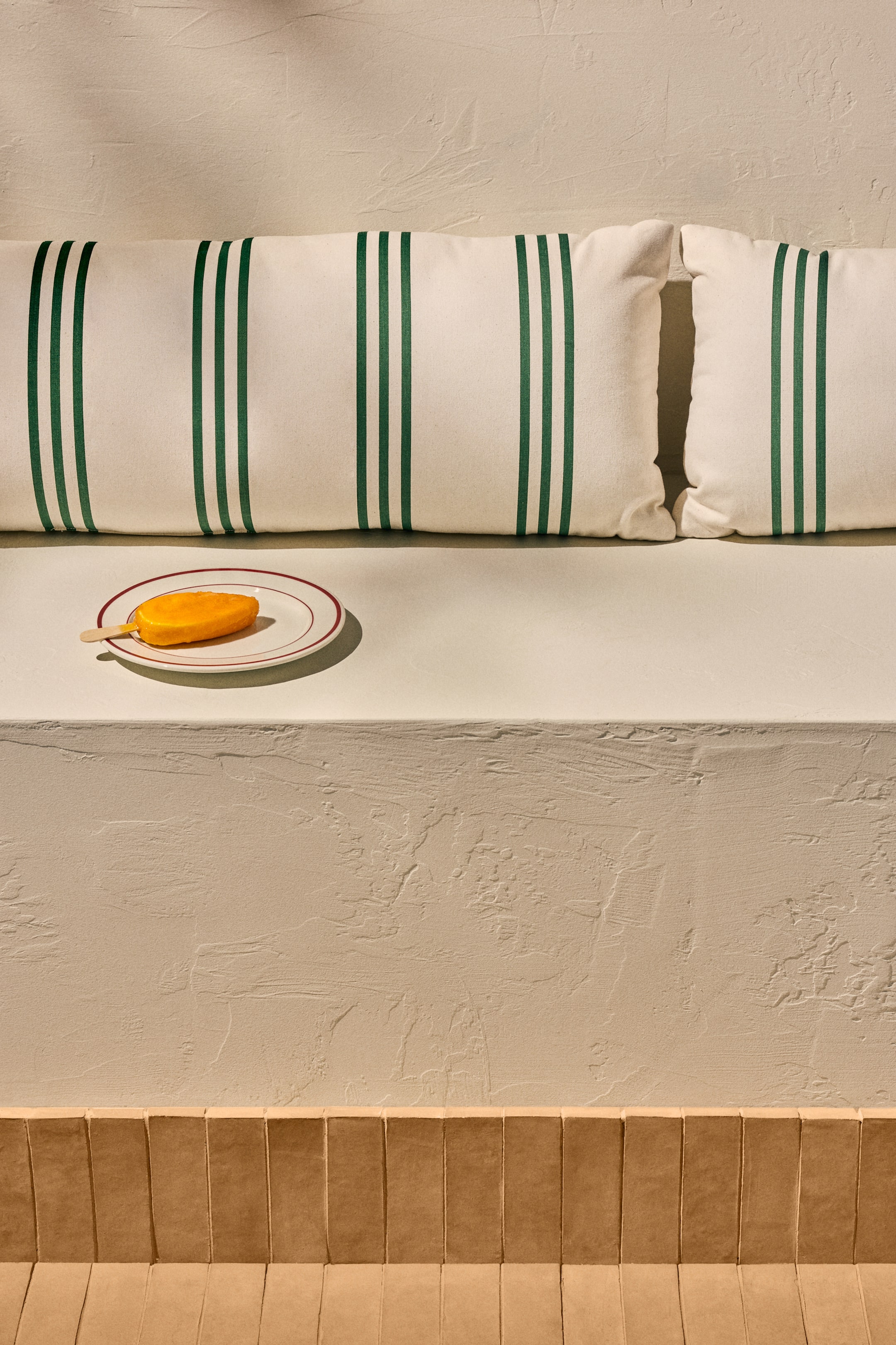 Agrandir l'image: Un coussin rectangulaire en toile de coton déperlant présente un fond blanc cassé avec des rayures triples verticales vert foncé. Il est présenté de face, avec un autre coussin identique à côté, adapté à une utilisation en extérieur.