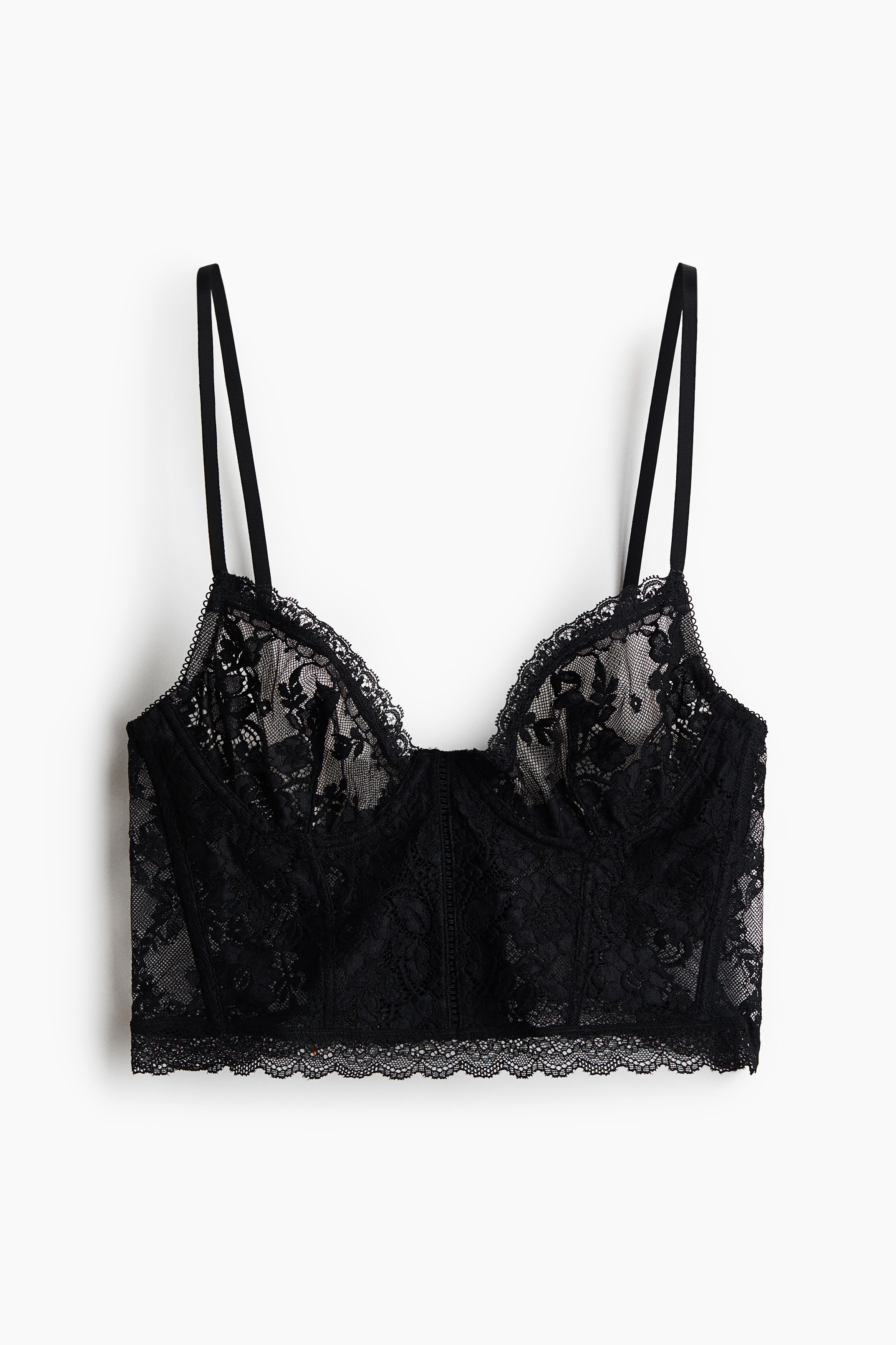 A black lace bustier featuring underwired cups, vertical boning and thin shoulder straps is being worn by the model, paired with matching black lace briefs.
