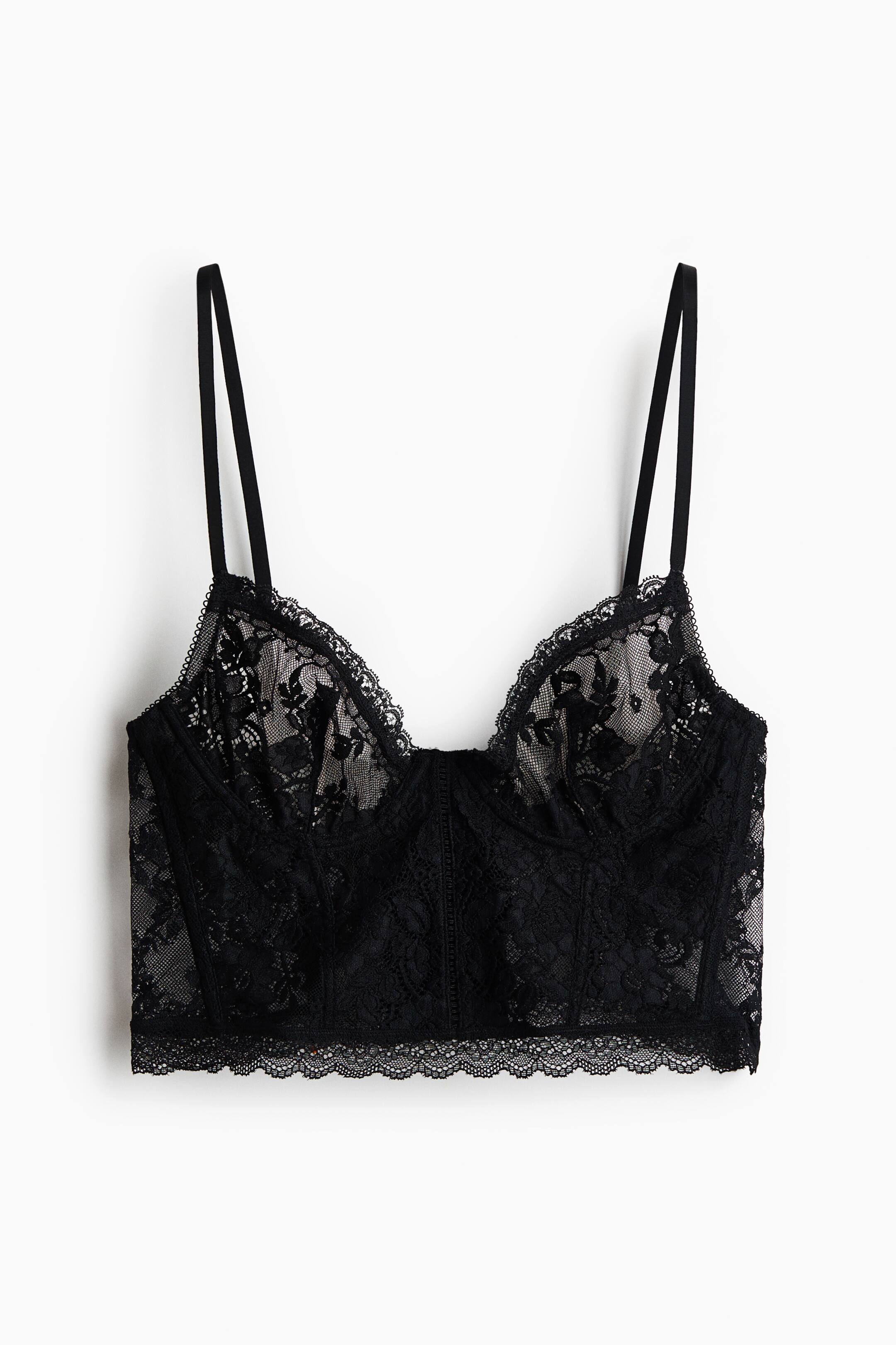 View larger image: A black lace bustier is shown from the front, featuring underwired cups in semi-sheer floral lace and thin, adjustable shoulder straps. The structured bodice features vertical boning channels and is finished with scalloped lace trim along the sweetheart neckline and bottom hem.