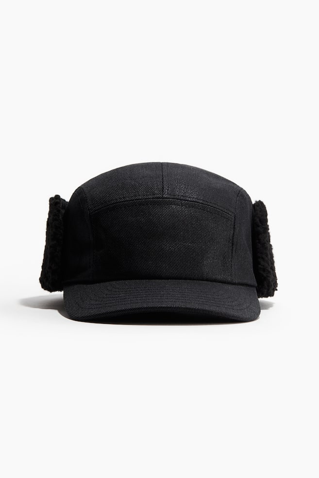 A black 5-panel cap is presented front-facing, featuring a flat brim. Its woven fabric body is complemented by two plush, black ear flaps that are extending downwards from the sides. - 1
