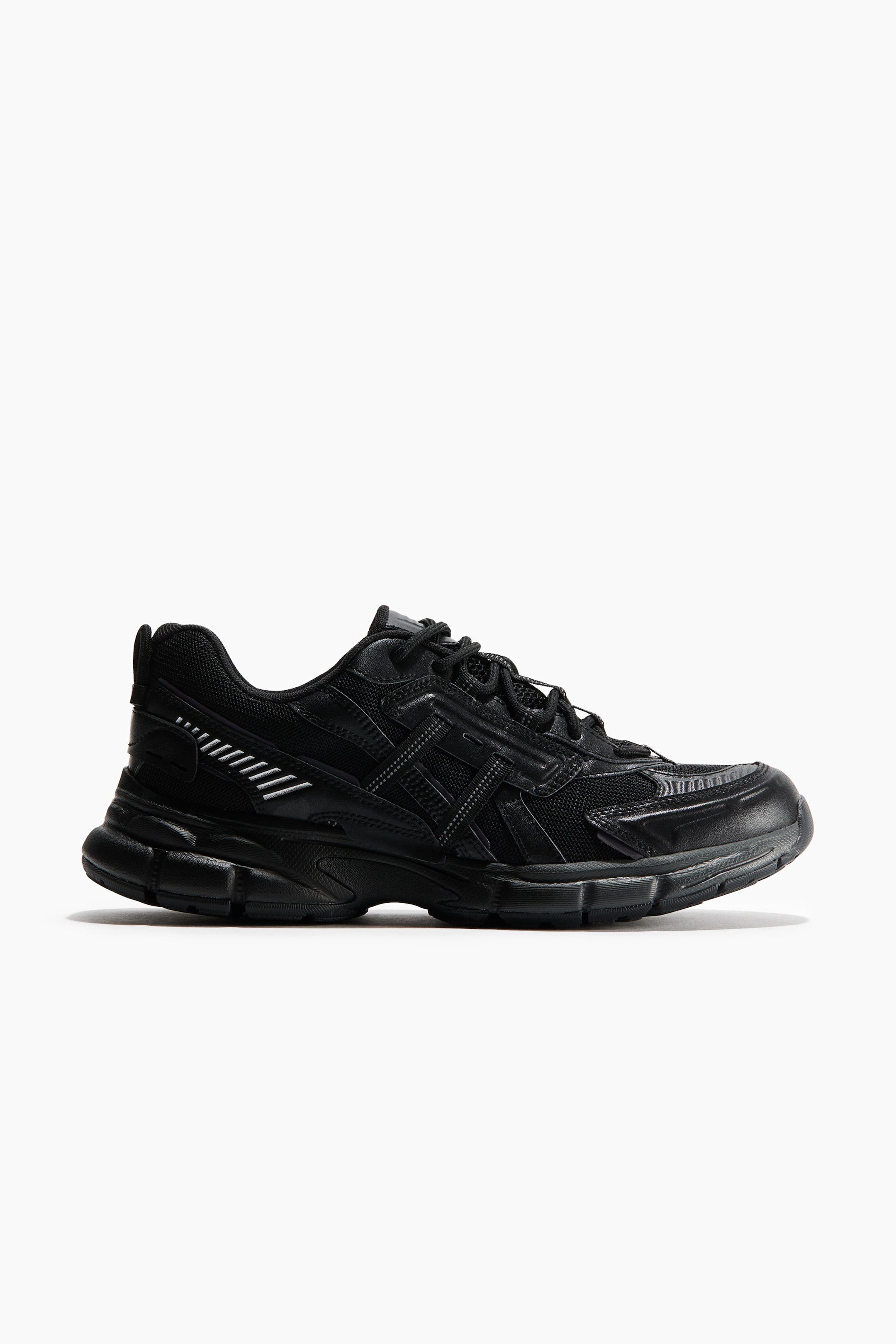 View larger image: A black sneaker showcases its side profile, highlighting a chunky sole with textured detailing, mesh panels, and synthetic overlays. Light-coloured horizontal lines appear on the rear quarter panel, and black laces secure the upper.