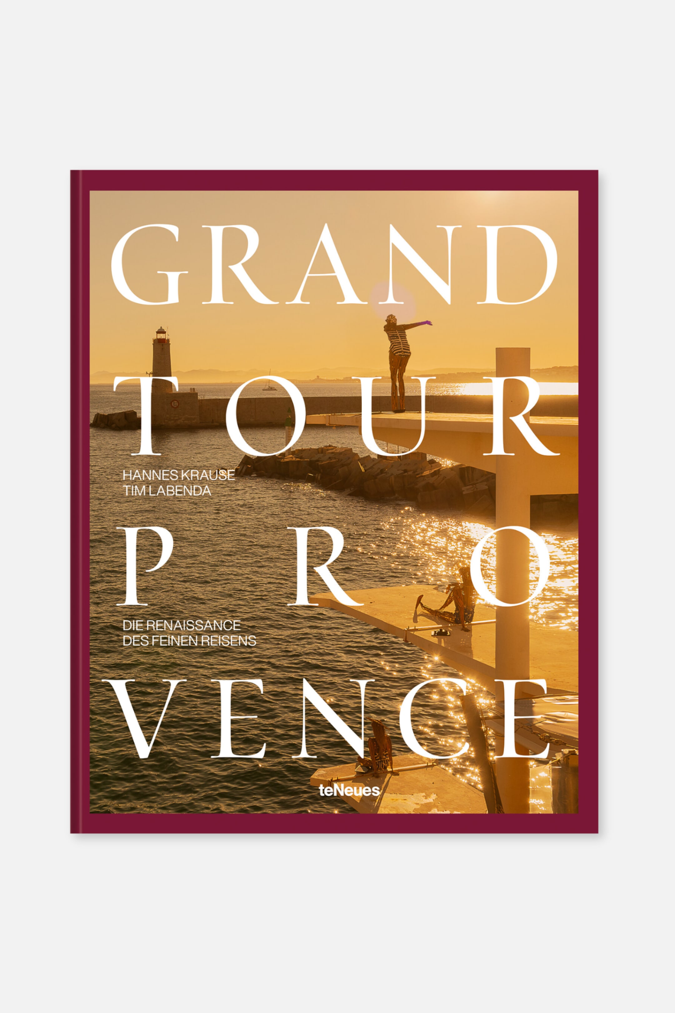 Größeres Bild anzeigen: Ein Buch wird frontal präsentiert und zeigt ein Cover mit einer fotografischen Szene eines Leuchtturms und Figuren auf einem Pier bei Sonnenuntergang oder Sonnenaufgang. Der Titel "GRAND TOUR PROVENCE" ist in großen weißen Serifenschrift prominent gedruckt, mit kleinerem weißen Text, der die Autoren, einen Untertitel und das Verlagslogo identifiziert, alles eingerahmt von dunkelroten Rändern und einem dünnen Rahmen.