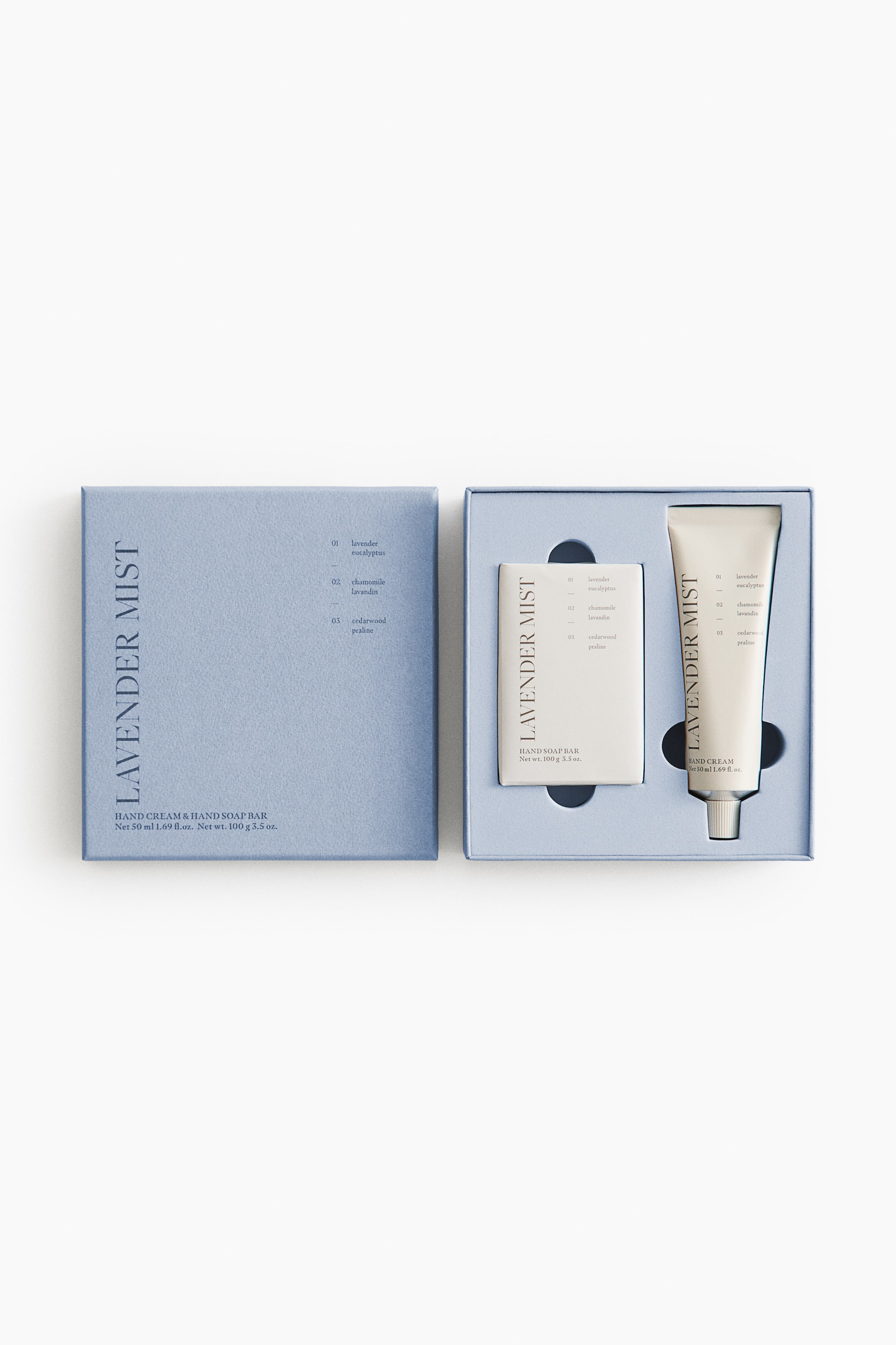 Ver imagen más grande: Un conjunto de crema de manos y pastilla de jabón de manos 'Lavender Mist' se presenta en una caja de regalo rectangular azul claro abierta. La tapa de la caja, que yace plana a la izquierda, muestra el nombre del producto y los aromas enumerados, mientras que la base sostiene una pastilla de jabón de manos blanca 'LAVENDER MIST' y un tubo de crema de manos blanca a juego con un tapón plateado.