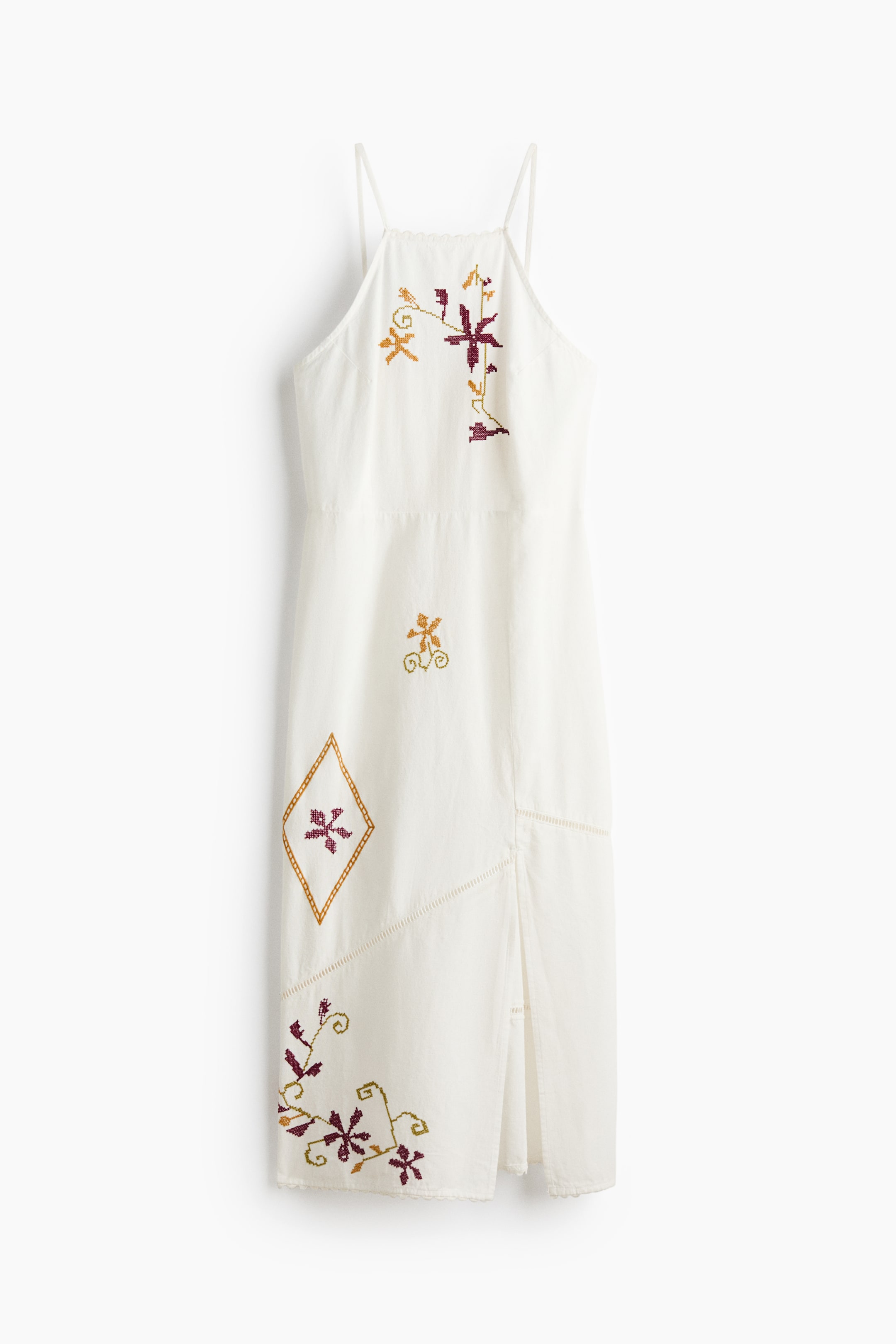 Größeres Bild anzeigen: Ein weißes Midikleid präsentiert sich von vorne, mit dünnen Spaghettiträgern und einem geraden Ausschnitt. Das Kleid zeigt verschiedene gestickte Muster in Burgunderrot, Gold und Grün, darunter florale Motive und eine markante Rautenform, ergänzt durch dekorative vertikale Nähte und einen seitlichen Schlitz.