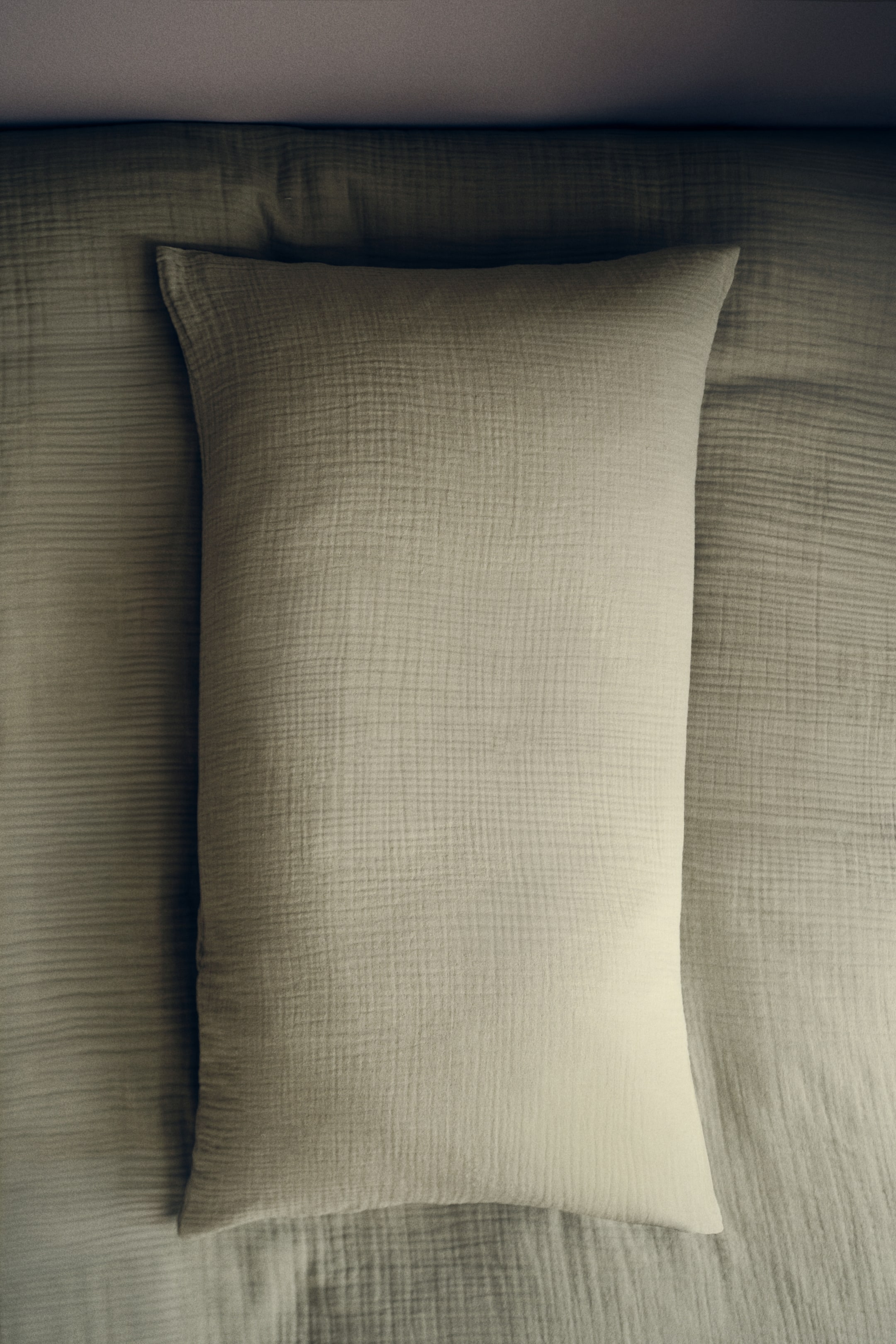 View larger image: A rectangular pillow lies flat, facing upwards, showcasing a light sage green, textured gauze fabric, and is set on a matching textured surface.