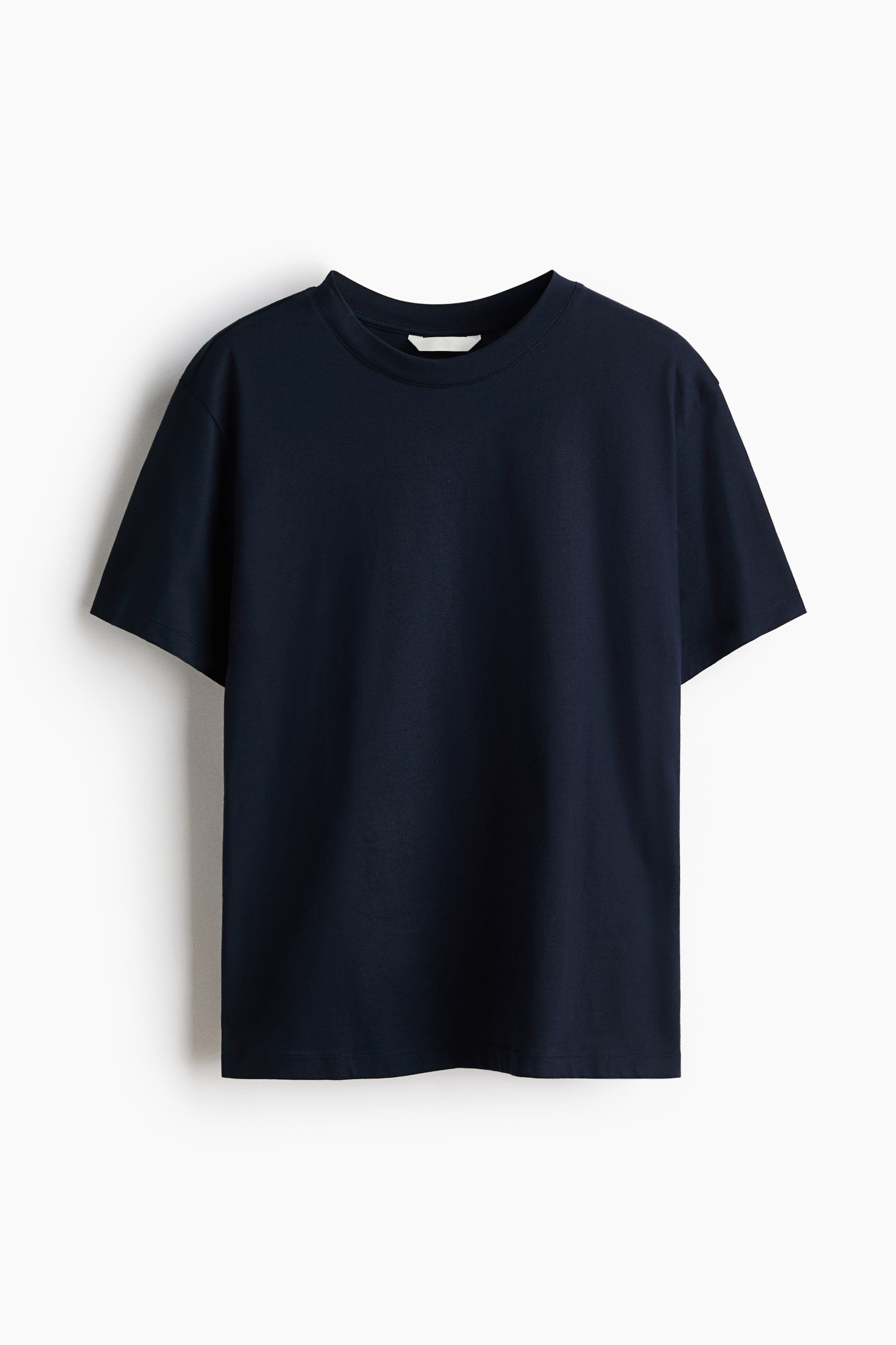 View larger image: A dark blue straight-cut t-shirt in soft cotton jersey is presented from the front, featuring a round, rib-trimmed neckline and gently dropped shoulders.