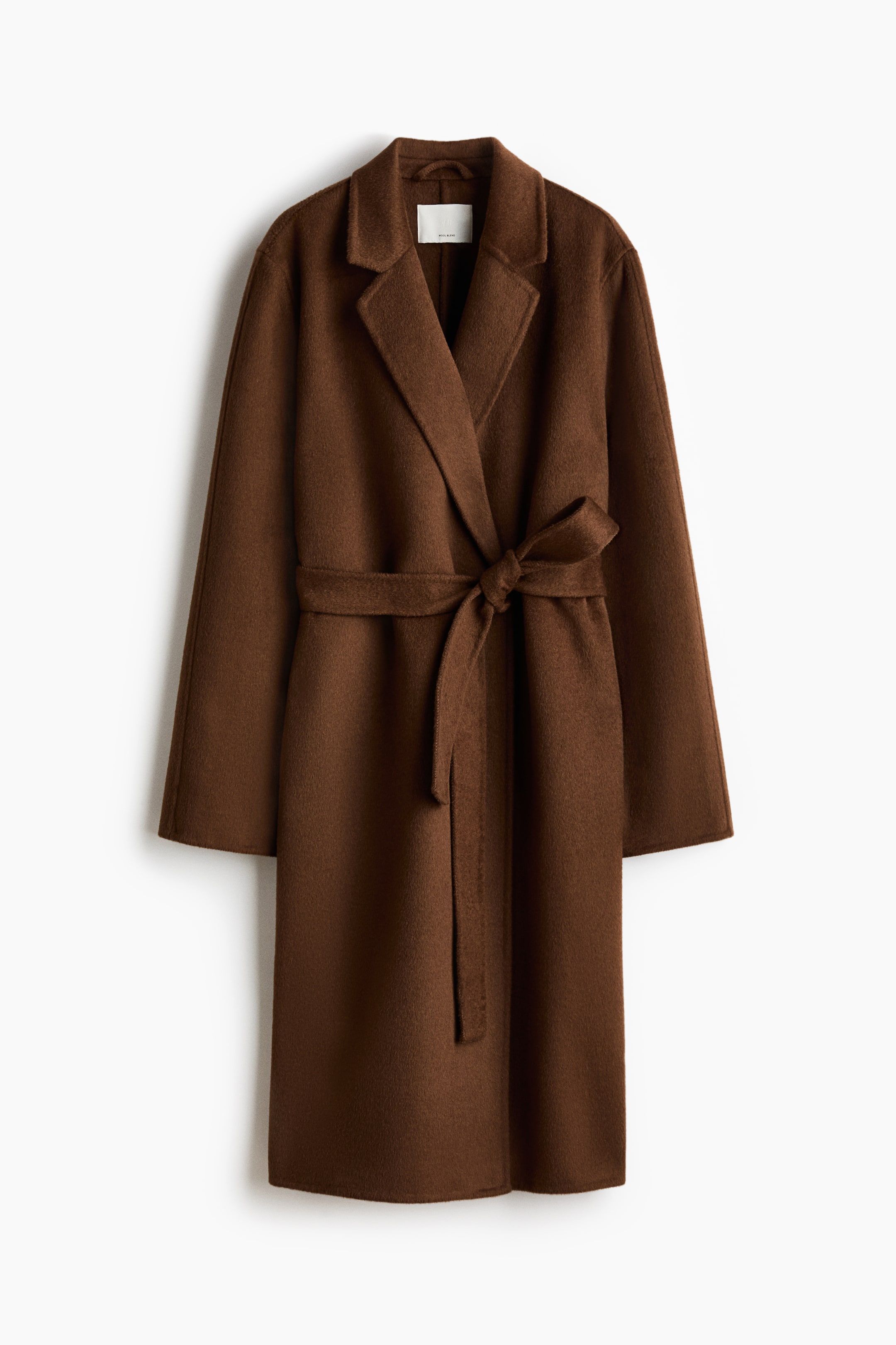 Ampliar la imagen: Un abrigo marrón de estilo cruzado con solapas amplias con muesca. Un cinturón del mismo tejido ciñe la cintura y se anuda al frente.