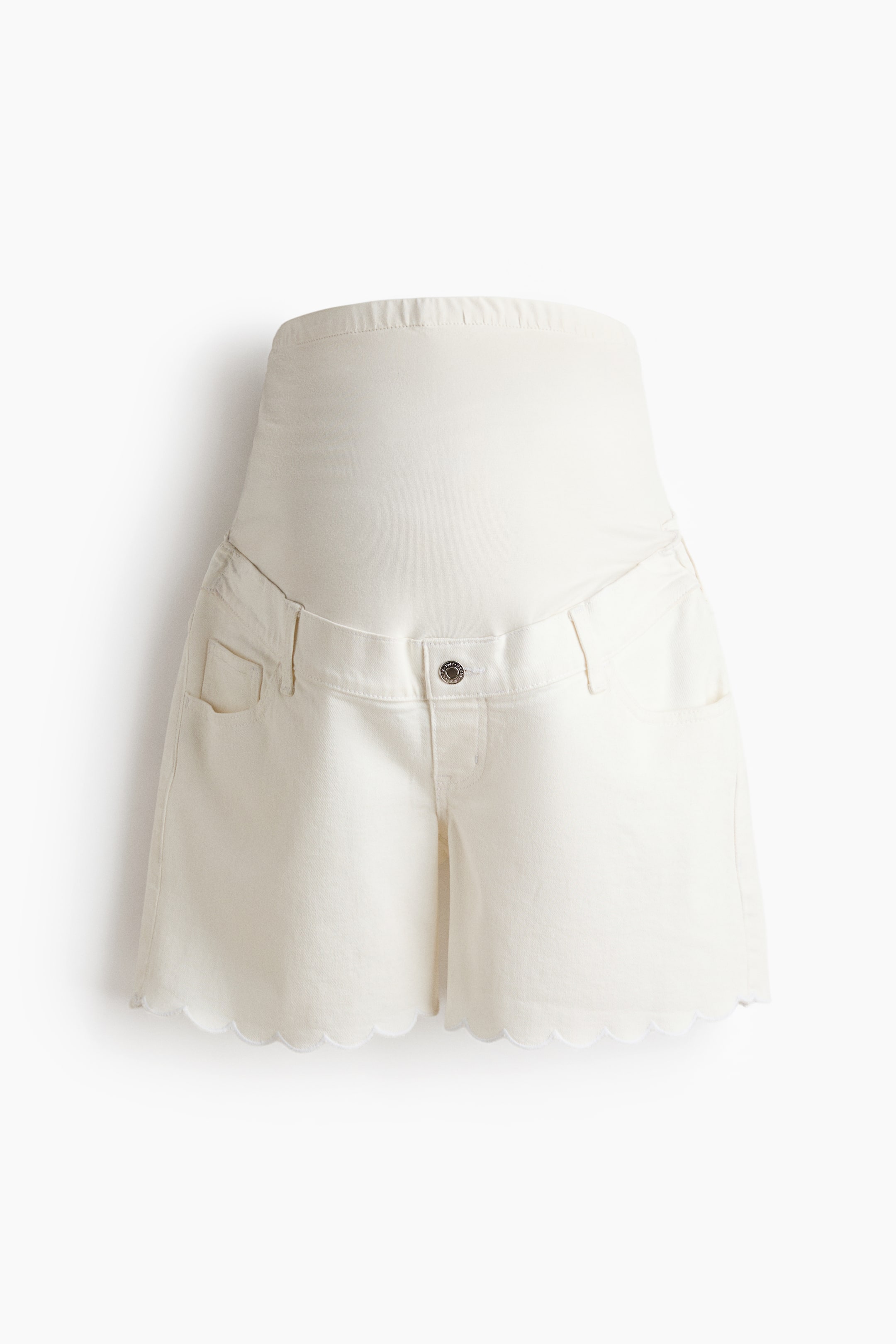 View larger image: Ecru maternity shorts are showcased at the front, boasting a high, elasticised knit panel. The shorts feature a single button closure, front pockets, and a unique scalloped hemline.
