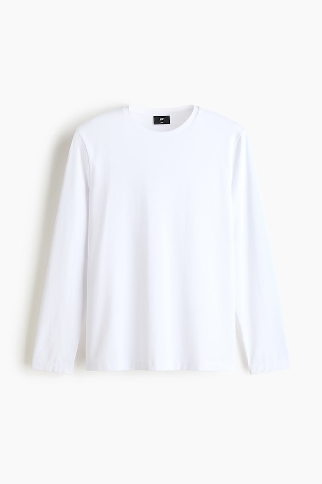 A white long-sleeve t-shirt is shown facing front, featuring a classic crew neck, long sleeves, and a straight hem. The garment is presenting a clean, minimalist design with a regular fit and a small black brand label visible inside the collar. - 1