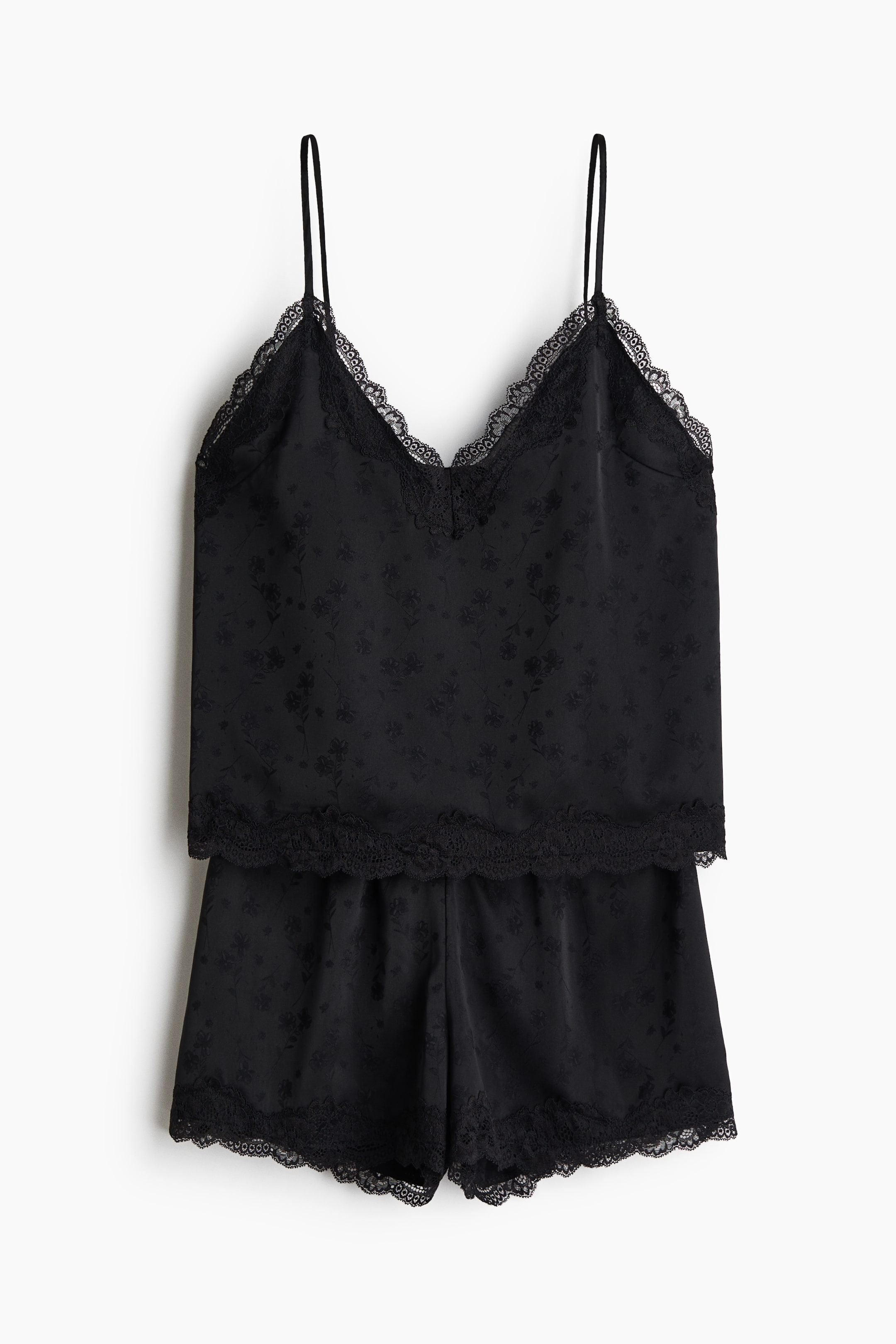Grotere afbeelding bekijken: Een vooraanzicht toont een zwarte satijnen pyjamaset met een camisole-top en bijpassende shorts met een subtiel bloemenpatroon. De top heeft dunne spaghettibandjes, een V-vormige halslijn en verfijnde kanten afwerkingen, terwijl de shorts zijn afgewerkt met een bijpassende zoom met kanten rand.