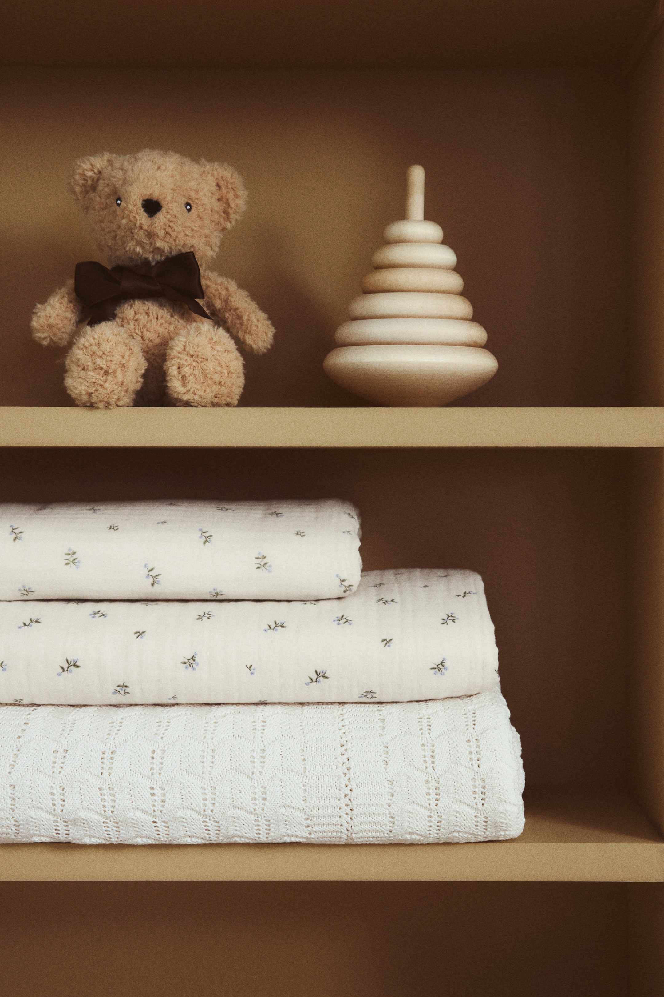 View larger image: A crib duvet cover and a matching pillowcase are neatly folded and stacked. The soft cotton muslin fabric features an all-over print of small blue floral patterns.