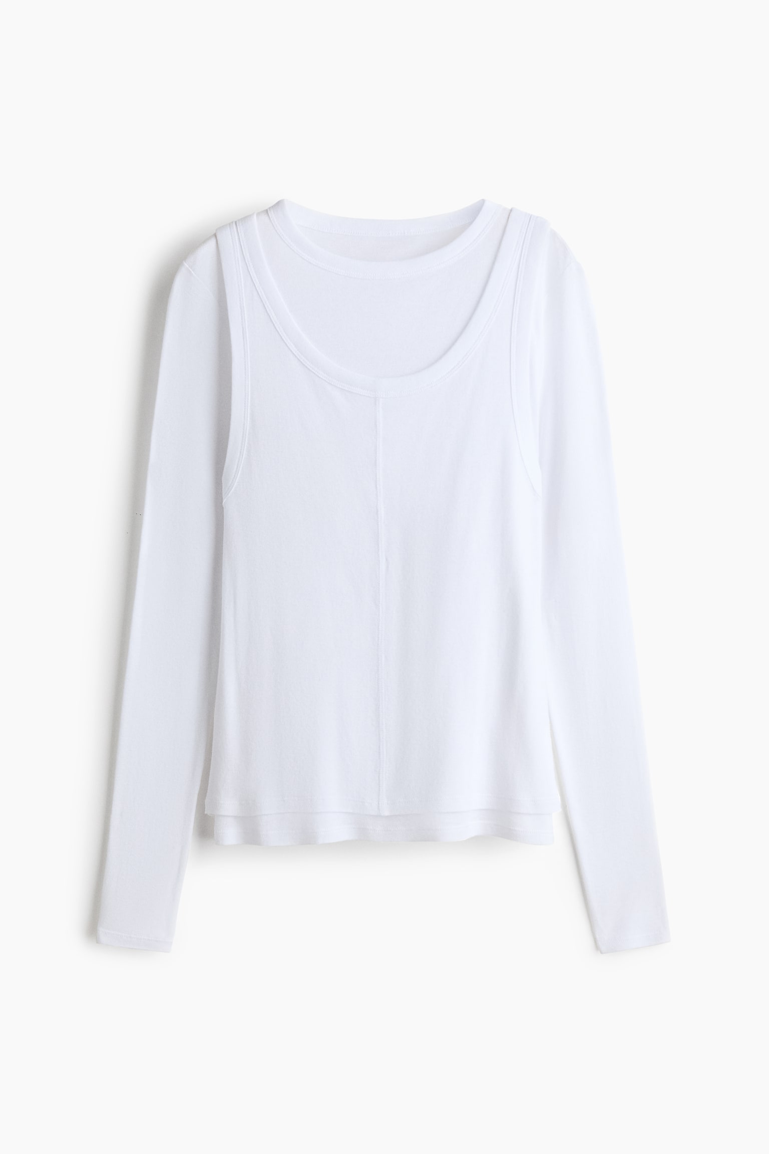Un haut blanc superposÃ© est prÃ©sentÃ© de face, mettant en valeur une base Ã  manches longues et col rond sous un dÃ©bardeur Ã  col rond dÃ©gagÃ©. Le dÃ©bardeur extÃ©rieur prÃ©sente une couture verticale au centre devant ainsi quâun ourlet lÃ©gÃ¨rement plus court, crÃ©ant un effet Ã  plusieurs niveaux. - 1