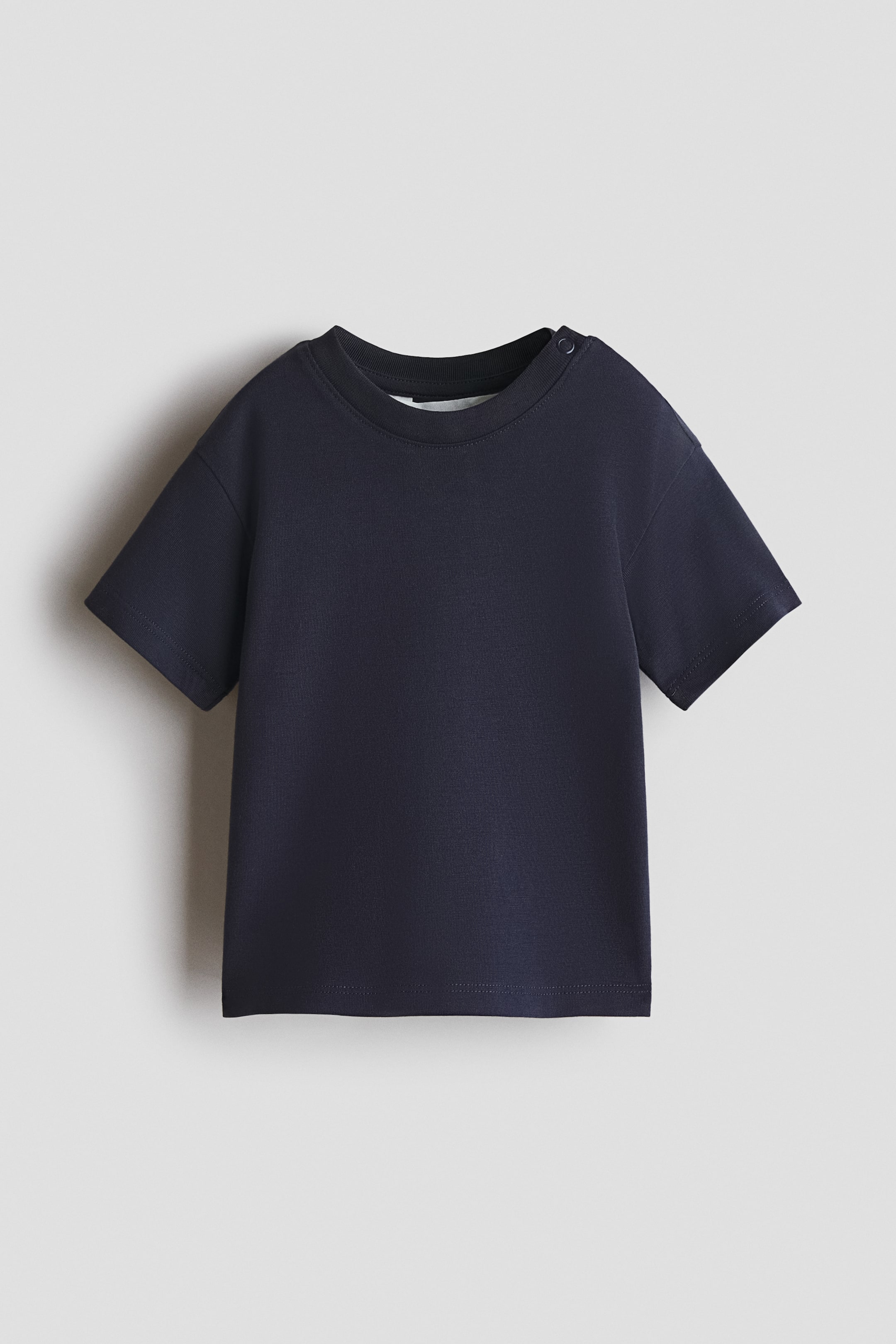 View larger image: Displayed is a navy loose-fit T-shirt, showcasing a round neckline with rib trim and two snap buttons on one side, dropped shoulders, and short sleeves.