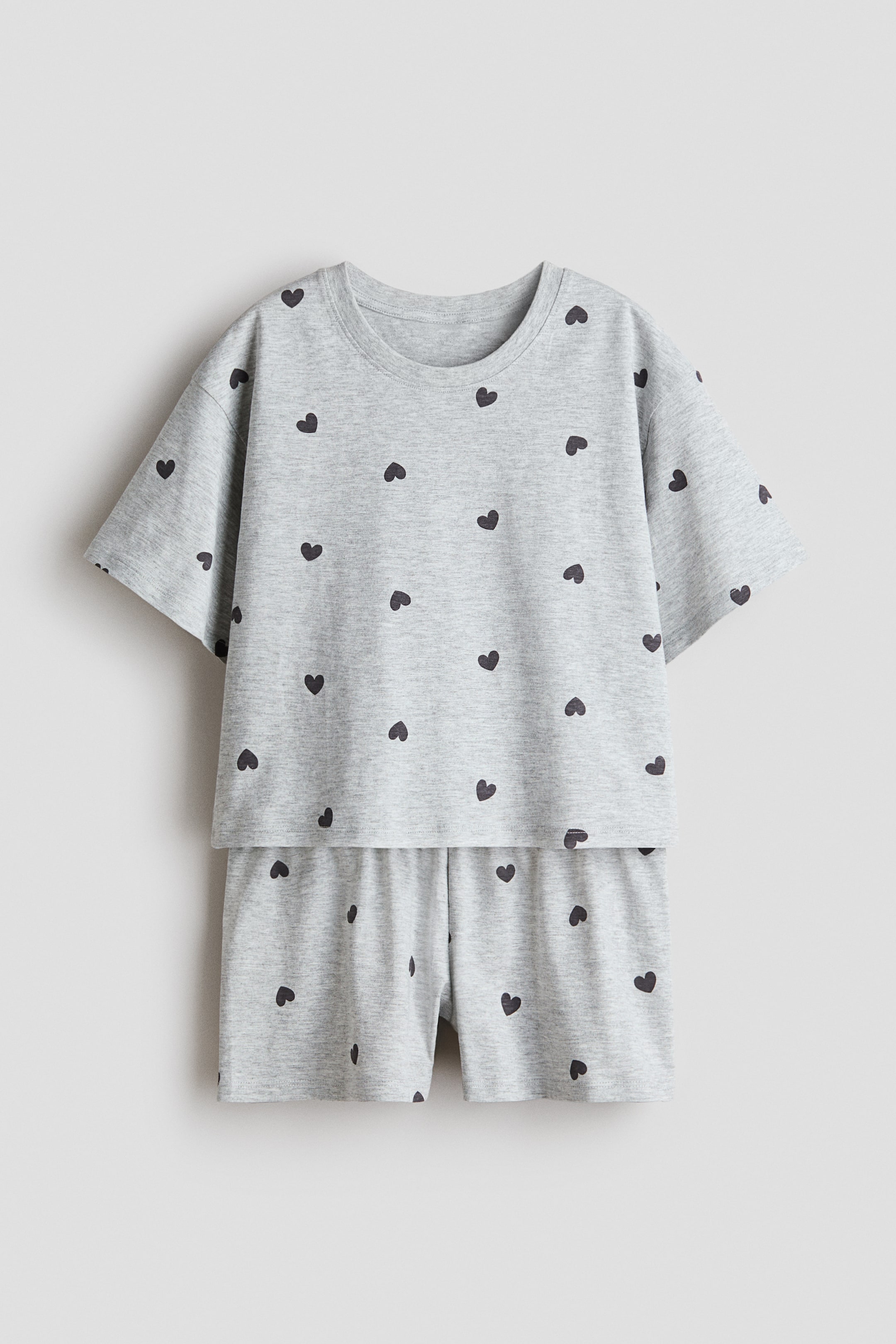 View larger image: Pyjamas in soft cotton jersey are showcasing FRONT, featuring a grey top with a round neckline, dropped shoulders, and short sleeves. The matching shorts boast an elasticated waist, and both pieces are adorned with small dark hearts.