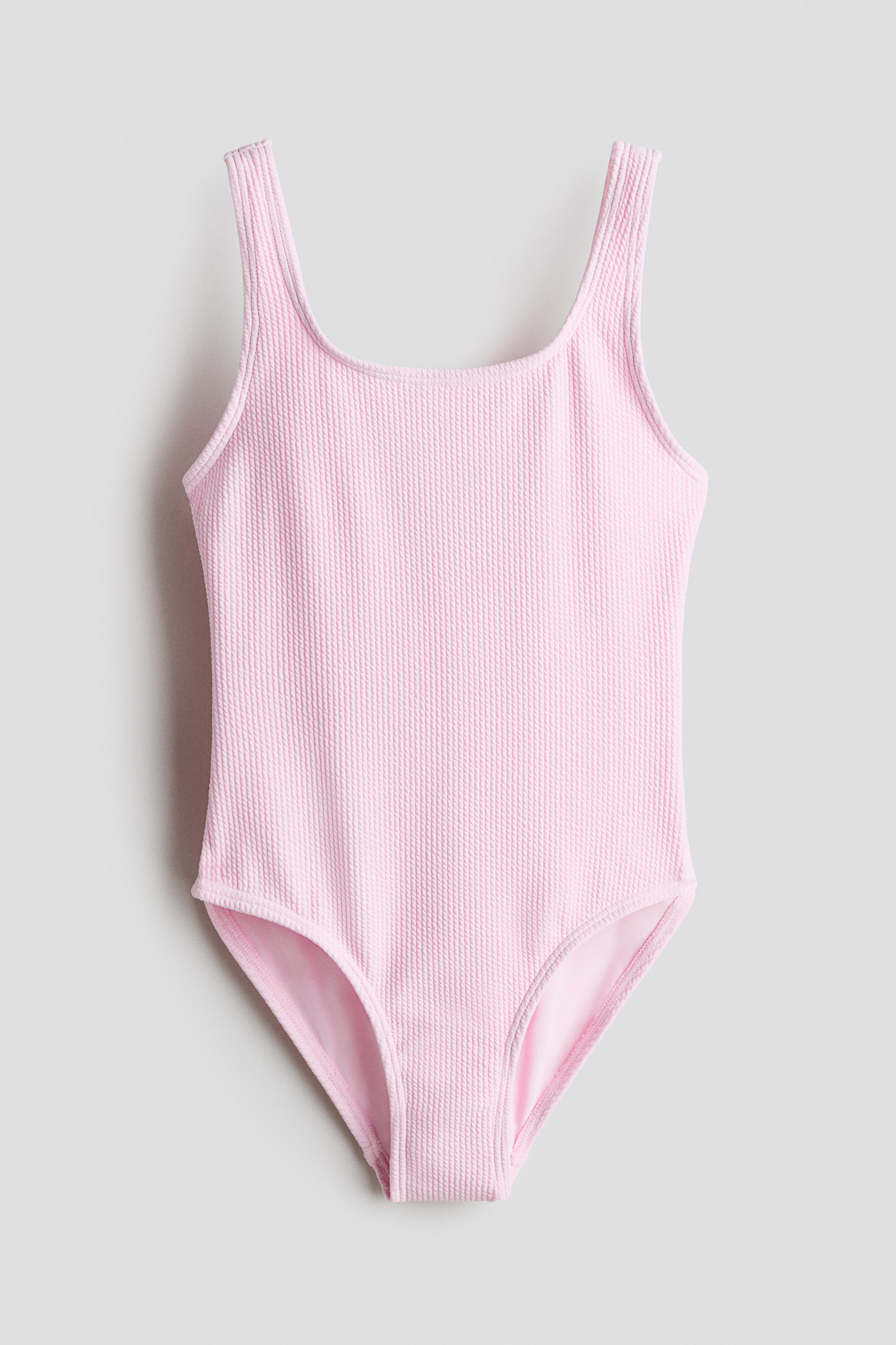 Grösseres Bild ansehen: Ein rosa geripptes Badeanzug wird von vorne präsentiert, mit einem runden Ausschnitt und vollständig gefütterter Konstruktion.