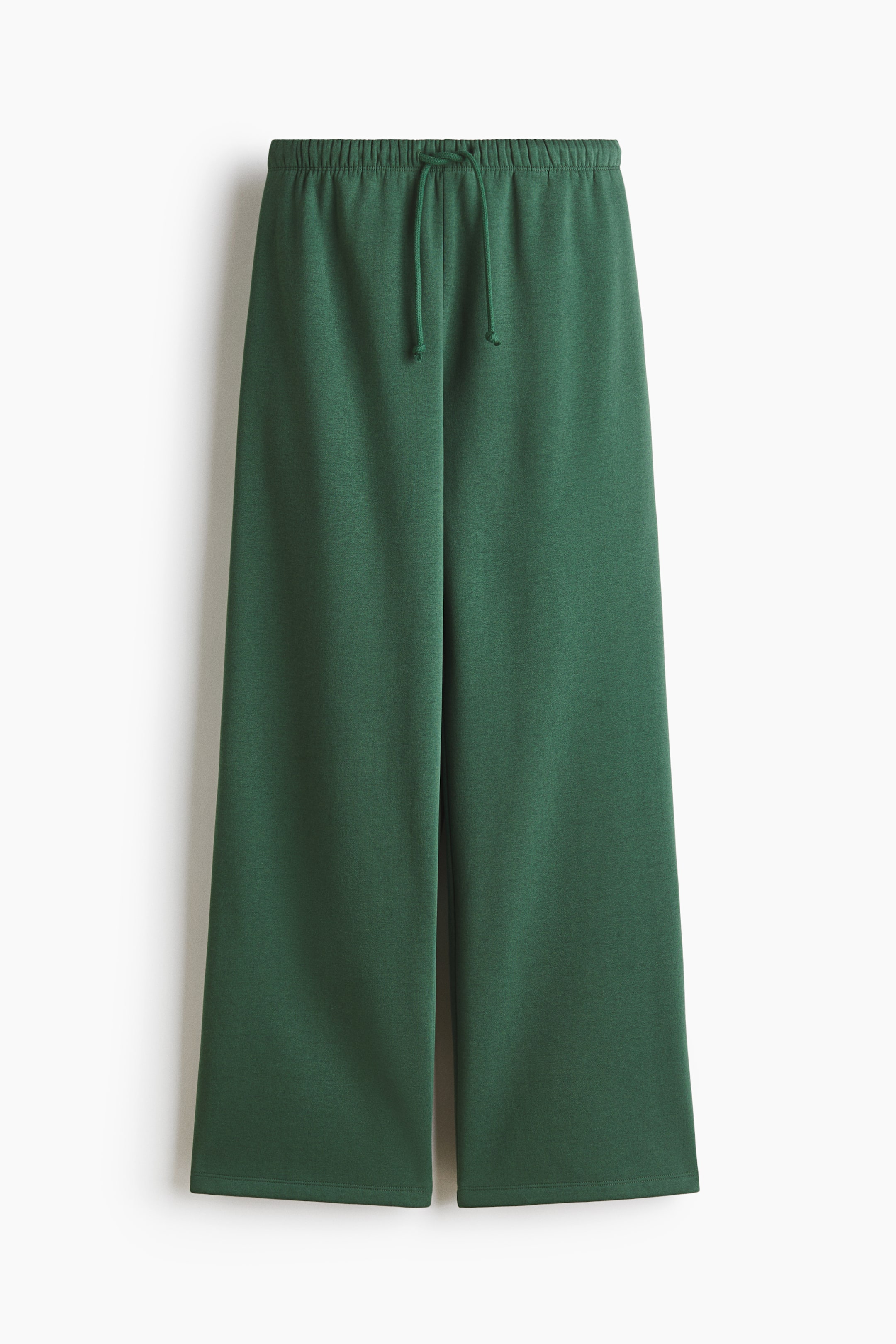 View larger image: Loose-fit green joggers are showcased in a front view, highlighting an elastic waistband with a tied drawstring and wide legs.
