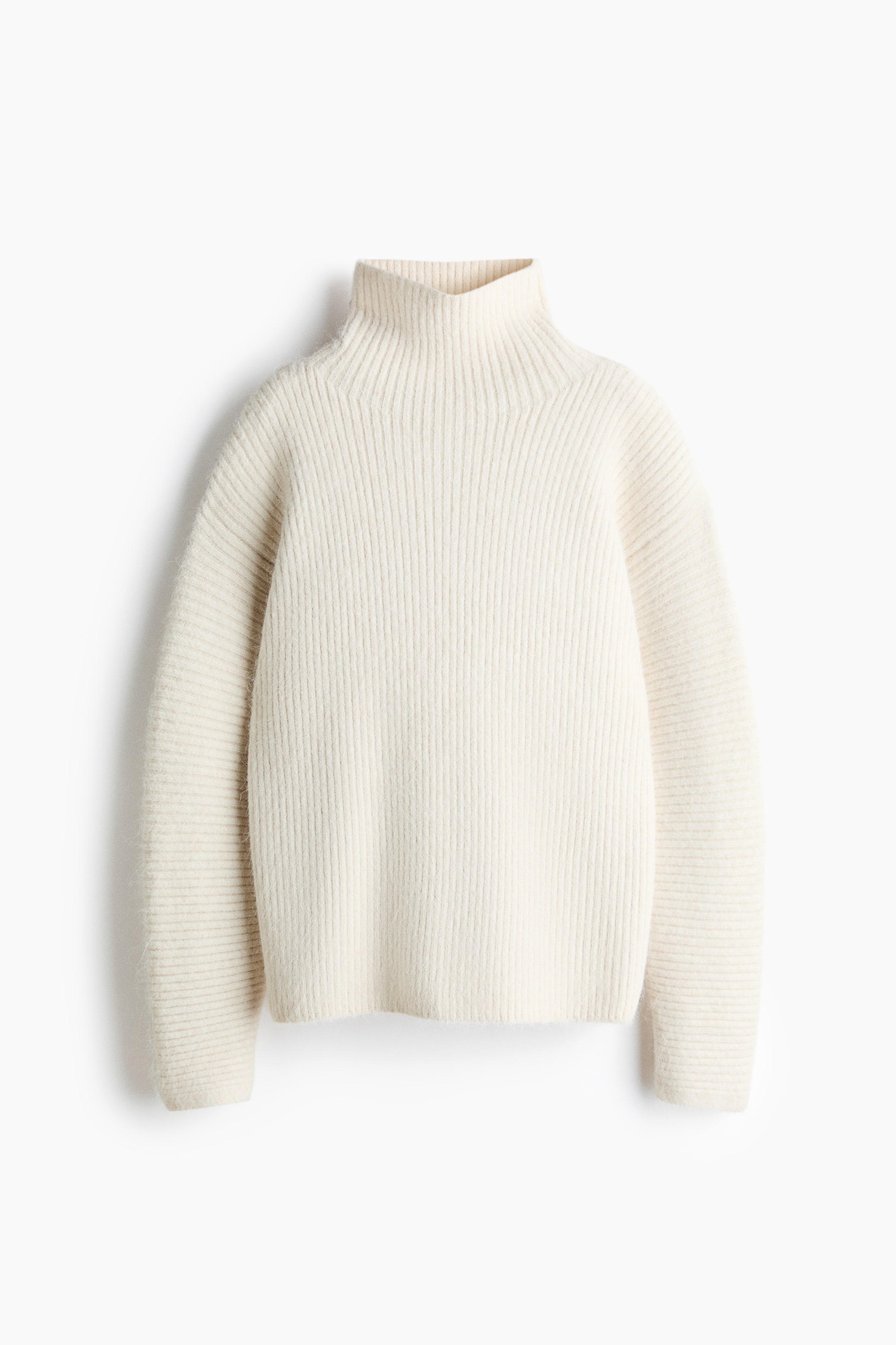 Größeres Bild ansehen: Ein cremefarbener, weicher Rippstrickpullover ist in Frontalansicht zu sehen und verfügt über einen hohen Rollkragen, überschnittene Schultern und lange Ärmel. Das Kleidungsstück zeigt eine vertikale Rippstruktur am Hauptteil sowie eine kontrastierende horizontale Rippstruktur an den Ärmeln.