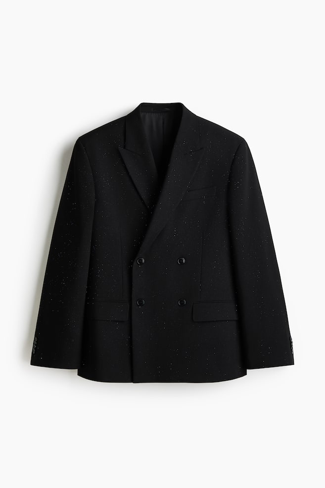 Eine schwarze zweireihige Jacke mit dezenten Glitzerpunkten wird von vorne präsentiert. Sie verfügt über Spitzrevers, eine paspelierte Brusttasche, zwei paspelierte Fronttaschen mit Klappen und dekorative Knöpfe an den Manschetten und zeigt eine lässige Passform. - 1