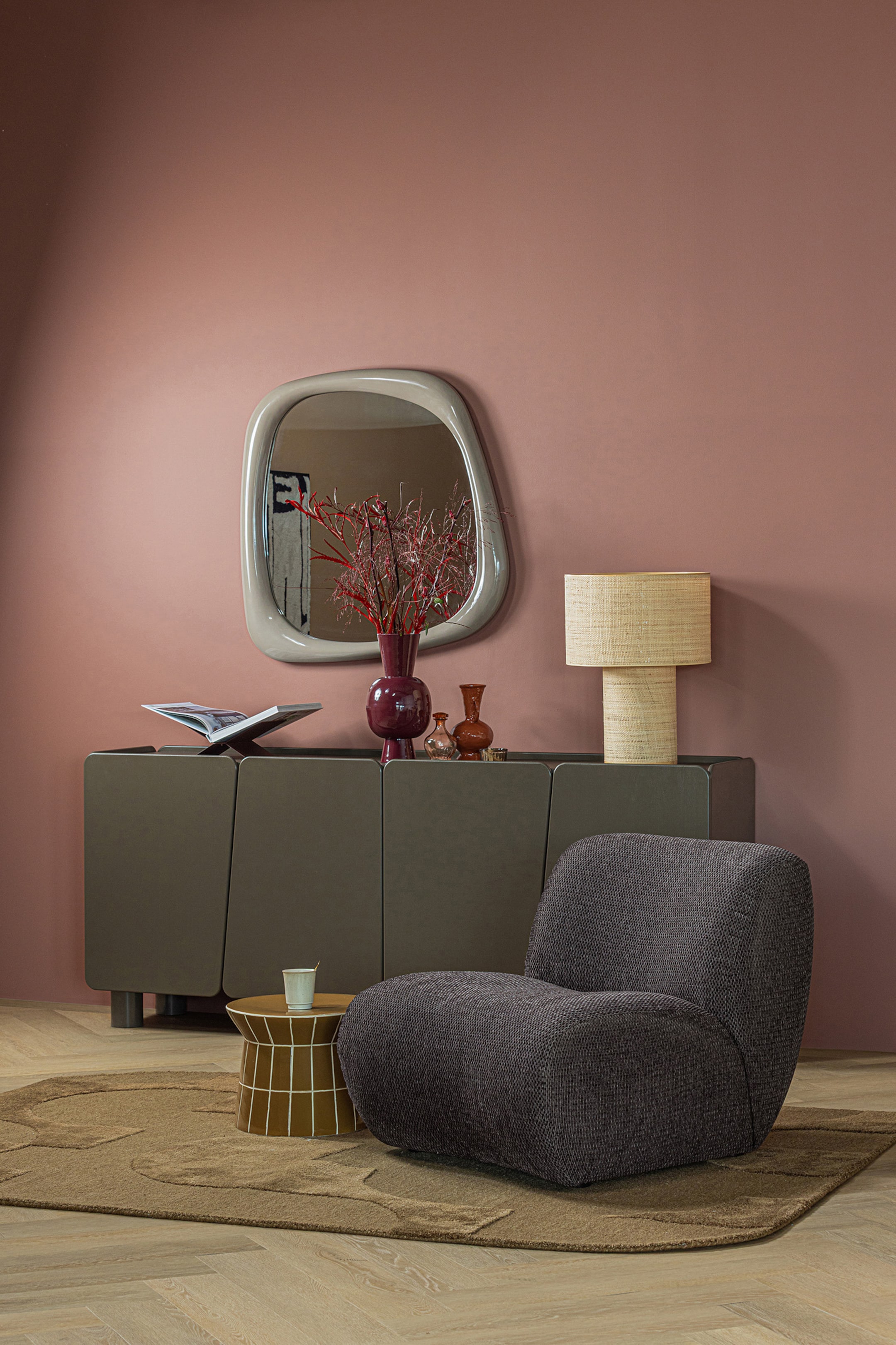 Agrandir l'image: Le fauteuil est recouvert d'un tissu texturé gris foncé, présentant un design bas et sans accoudoirs avec des contours arrondis. Il est légèrement orienté vers la droite et l'avant, mettant en valeur sa forme moelleuse et organique.