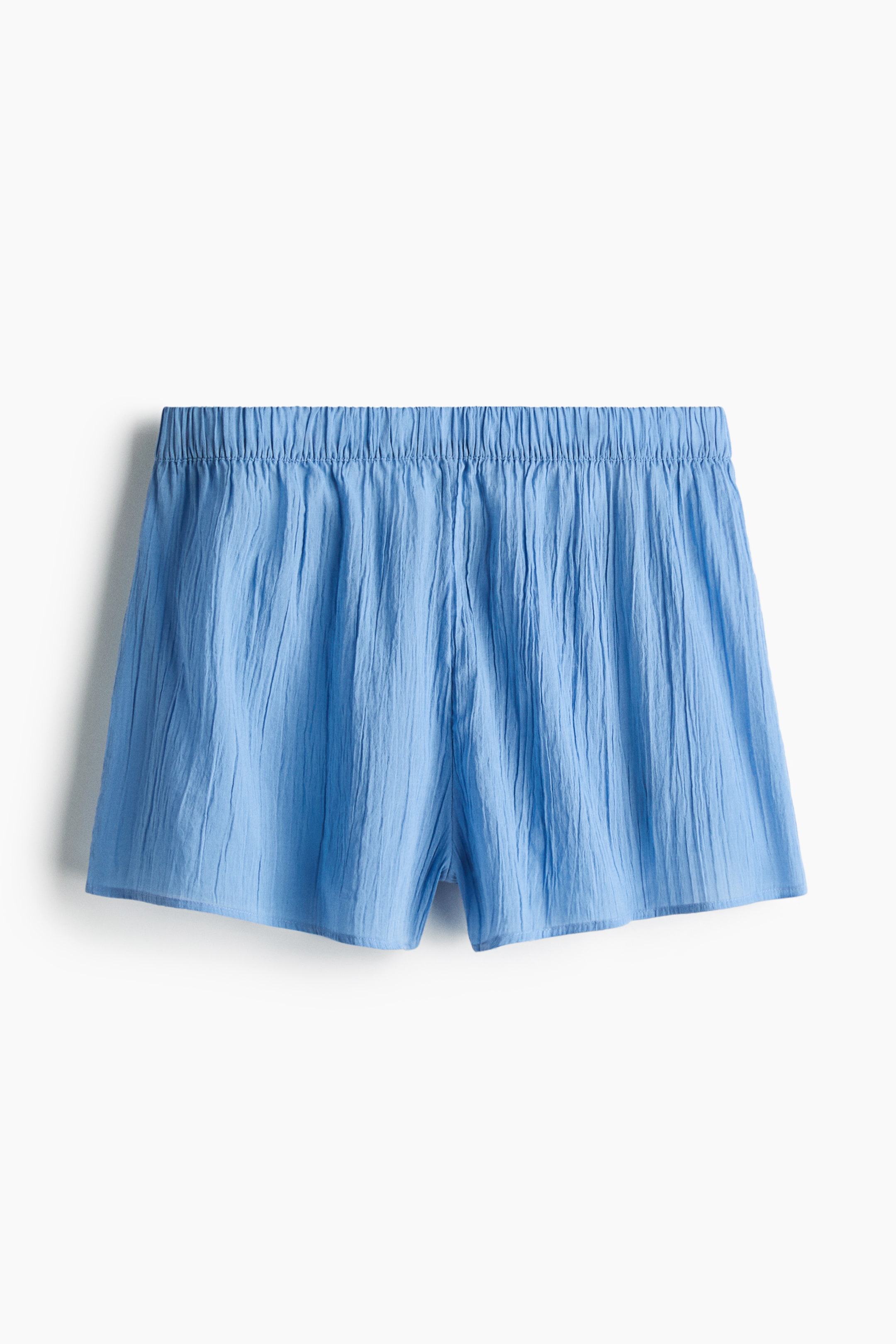 View larger image: Relaxed-fit shorts are displayed in a blue, crinkled cotton weave, featuring a gathered elasticated waist and shown from the front.