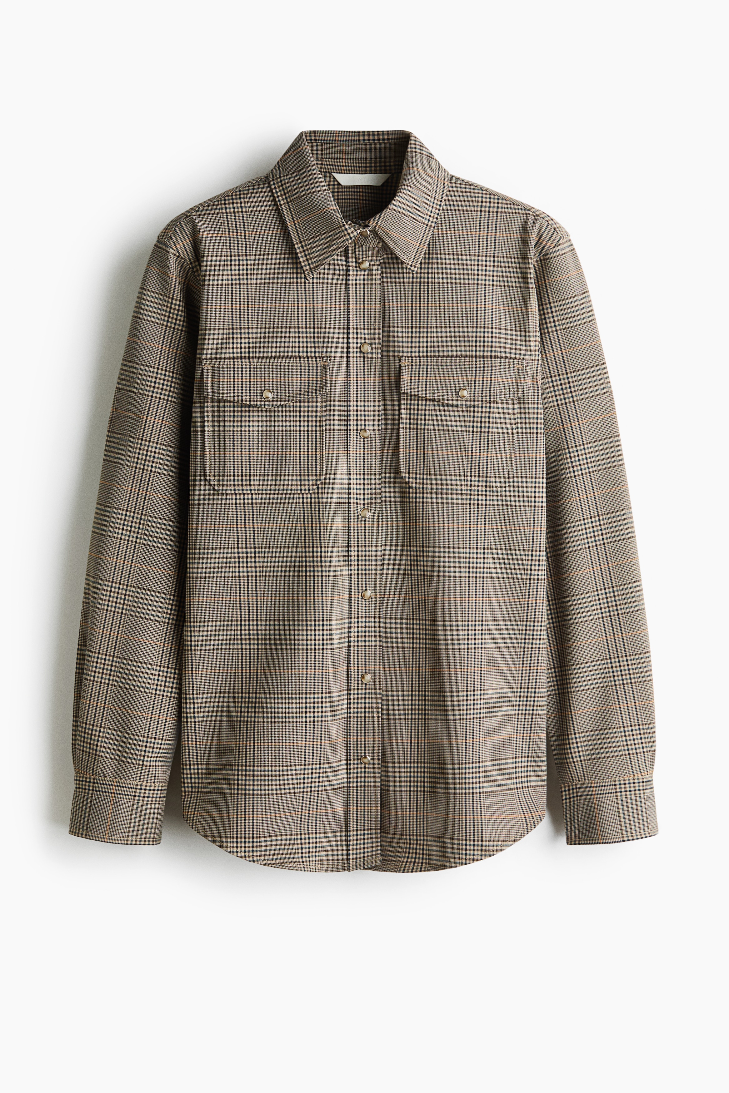 A woven checked shirt featuring a raised collar, silver press studs, and a flap chest pocket is being worn by the model. The shirt is layered over a black roll-neck top, showcasing its structured collar and patterned design from a side profile view.