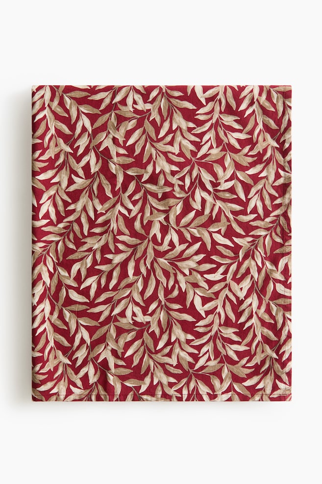 Une serviette en tissu carrÃ©e et pliÃ©e prÃ©sente un fond rouge profond avec un motif dense et rÃ©pÃ©titif de vignes feuillues beige et crÃ¨me. La serviette est orientÃ©e de face, mettant en valeur ses bords ourlÃ©s Ã  finition nette et son motif botanique. - 1