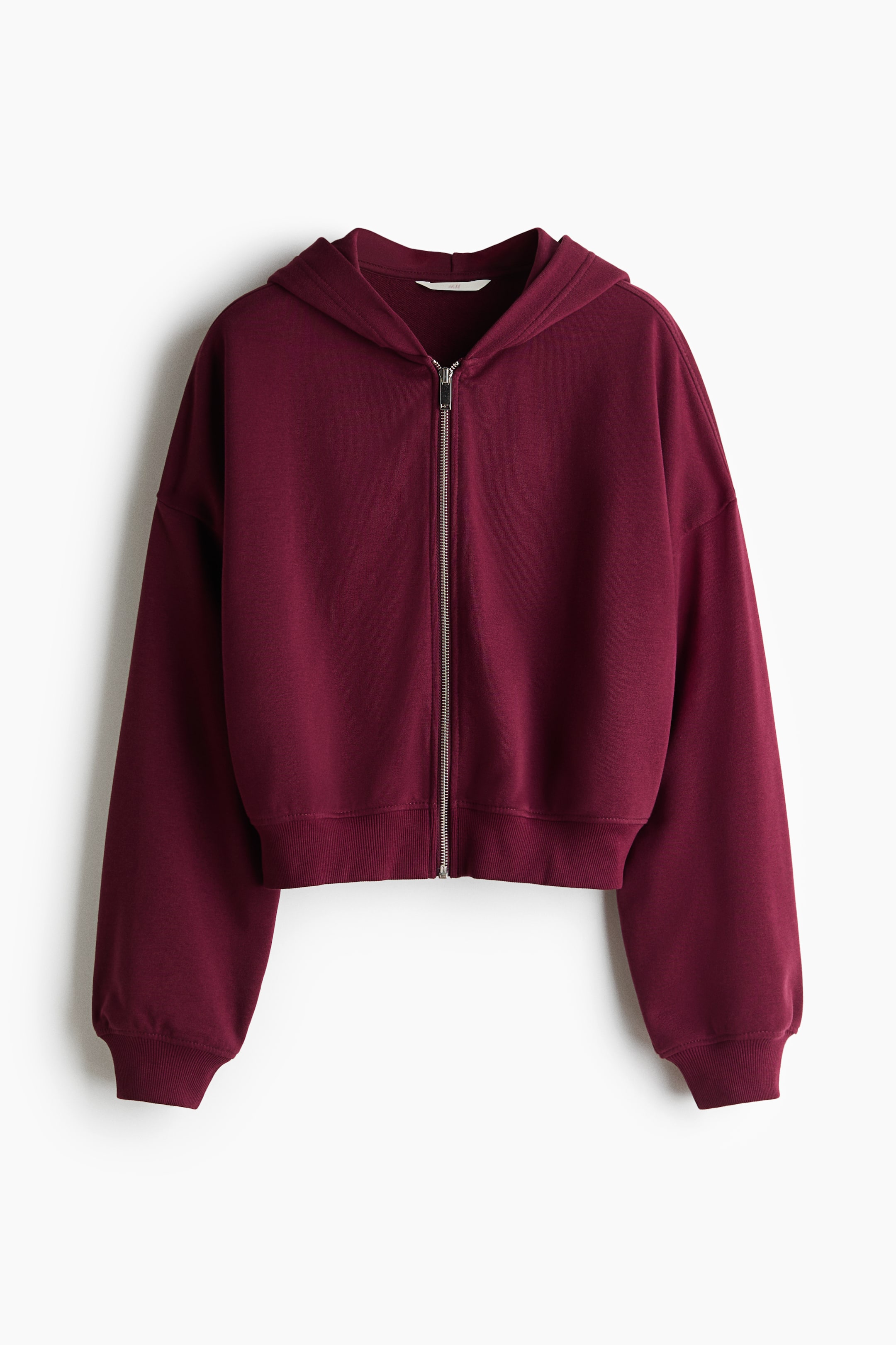 View larger image: A maroon cropped full-zip hoodie is shown from the front, featuring a silver-toned zipper, hood, dropped shoulders, and ribbed cuffs and hem.
