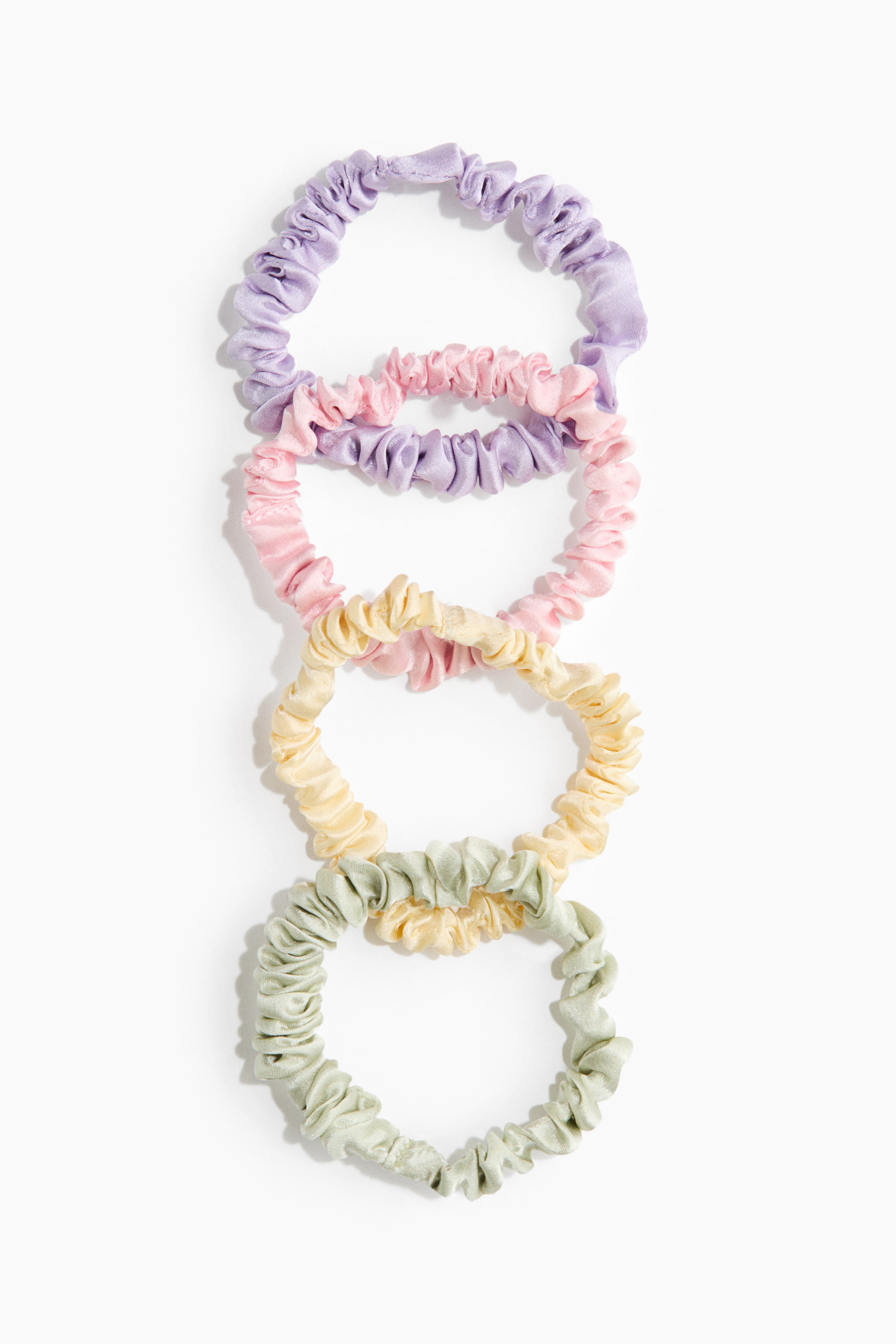 Grotere afbeelding bekijken: Vijf elastische scrunchies van moerbeizijde liggen plat en zijn verticaal met elkaar verbonden. Ze verschijnen in pastelkleuren van lavendel, roze, lichtgeel en twee lichtgroene tinten, allemaal met een zachte, geplooide textuur.