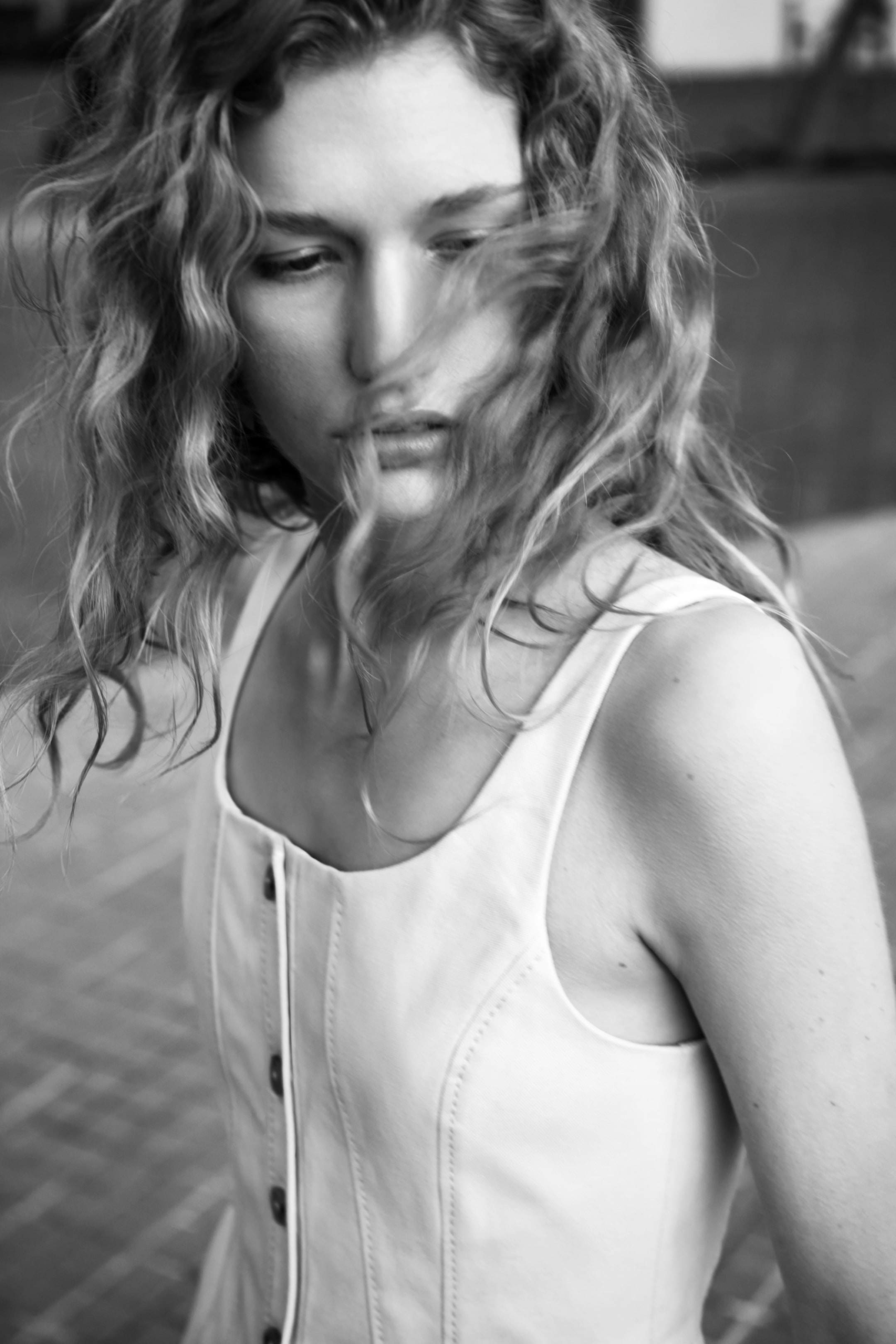 Zobacz większy obraz: Biały, dopasowany top w stylu gorsetu z szerokimi ramiączkami i kwadratowym dekoltem. Pionowa listwa guzikowa biegnie w dół środka przodu, prezentując ciemne guziki, podczas gdy pionowe detale szwów tworzą uporządkowany wygląd.