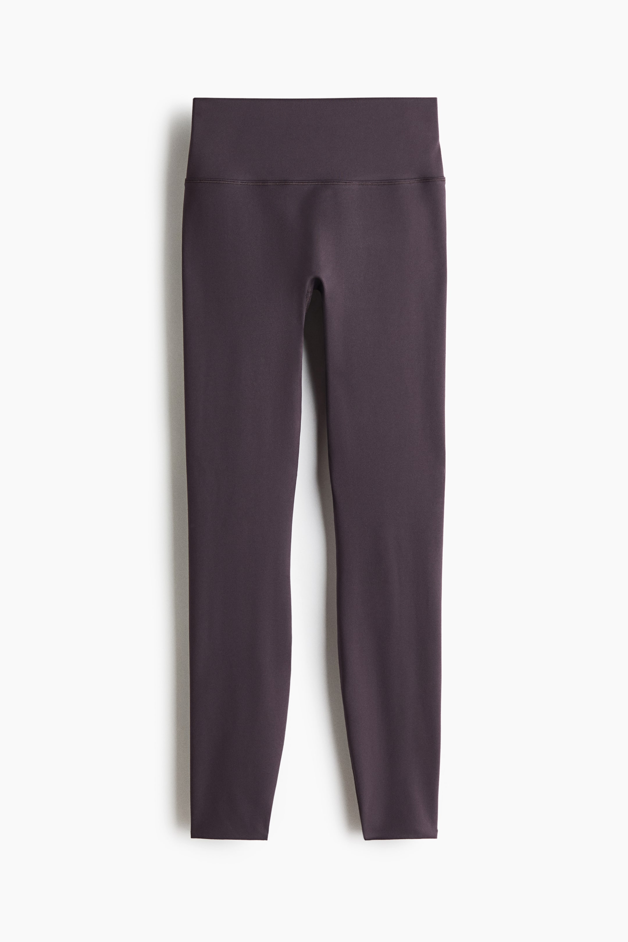 Ver imagen más grande: "Leggings deportivos de color morado oscuro presentados desde el frente. Cuentan con una amplia cintura de talle alto y un diseño suave y ajustado al cuerpo, con dobladillos limpios en los tobillos."