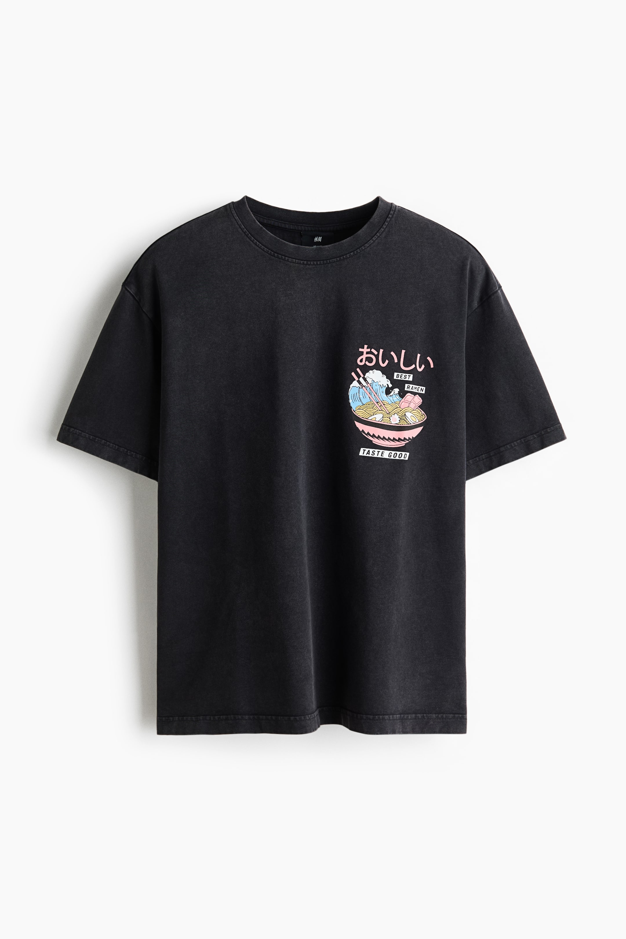 View larger image: A black T-shirt is shown from the front, featuring a ribbed crew neck and short sleeves. A colourful graphic appears on the left chest, depicting a pink bowl of ramen with blue waves, chopsticks, and the text '????', 'BEST RAMEN', and 'TASTE GOOD'.