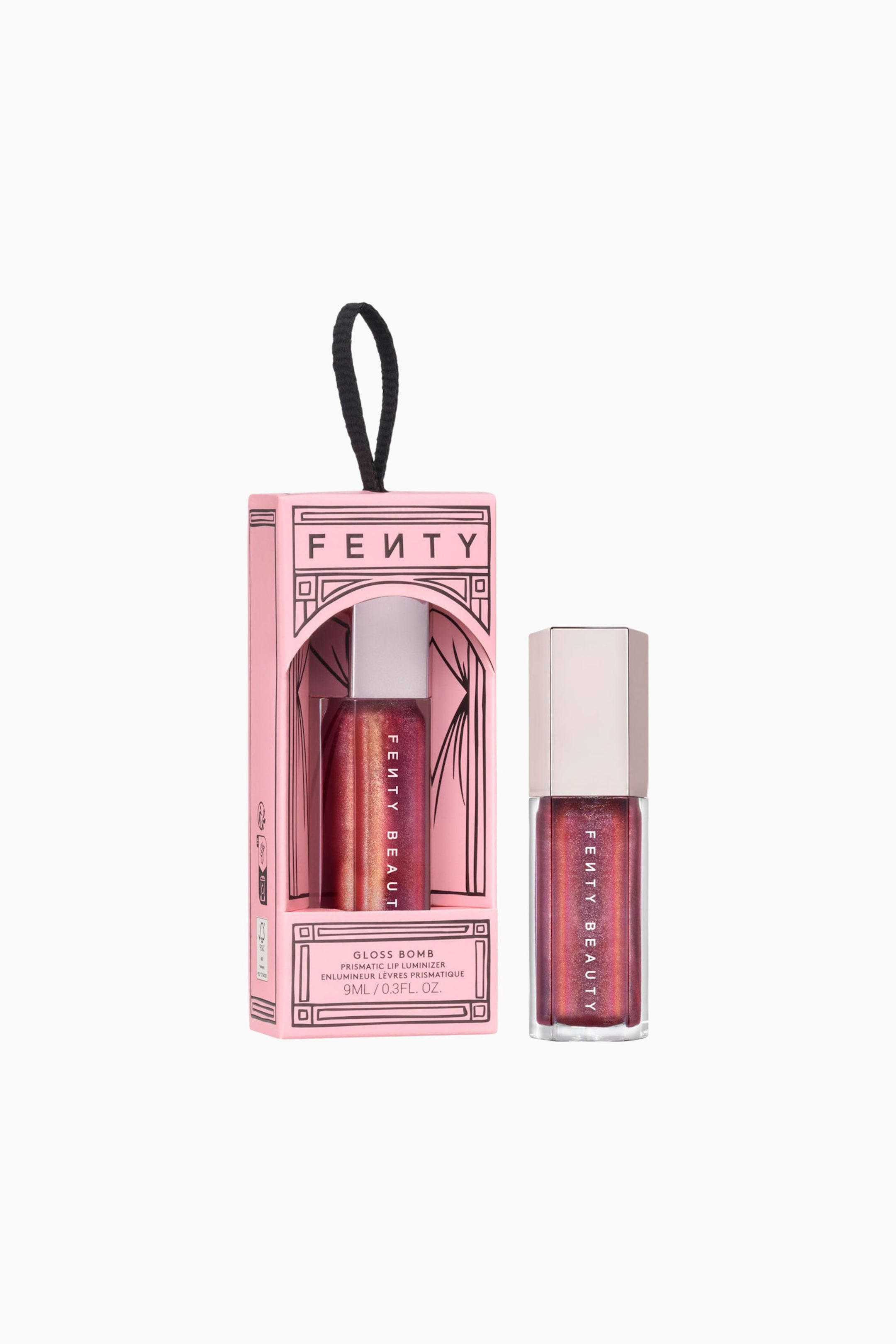 Visa större bild: Limited Edition Gloss Bomb Universal Lip Luminizer står upprätt bredvid sin rosa förpackning i ornamentstil, som har en svart bandögla upptill. Läppglanset visar upp en skimrande, prismatisk rödbronsfärgad nyans genom en transparent hexagonal flaska med vertikal vit varumärkesmärkning och är krönt med ett metalliskt roséguldfärgat lock. Den rosa asken har ett dekorativt välvt fönster som avslöjar ett identiskt läppglansrör som vilar inuti.