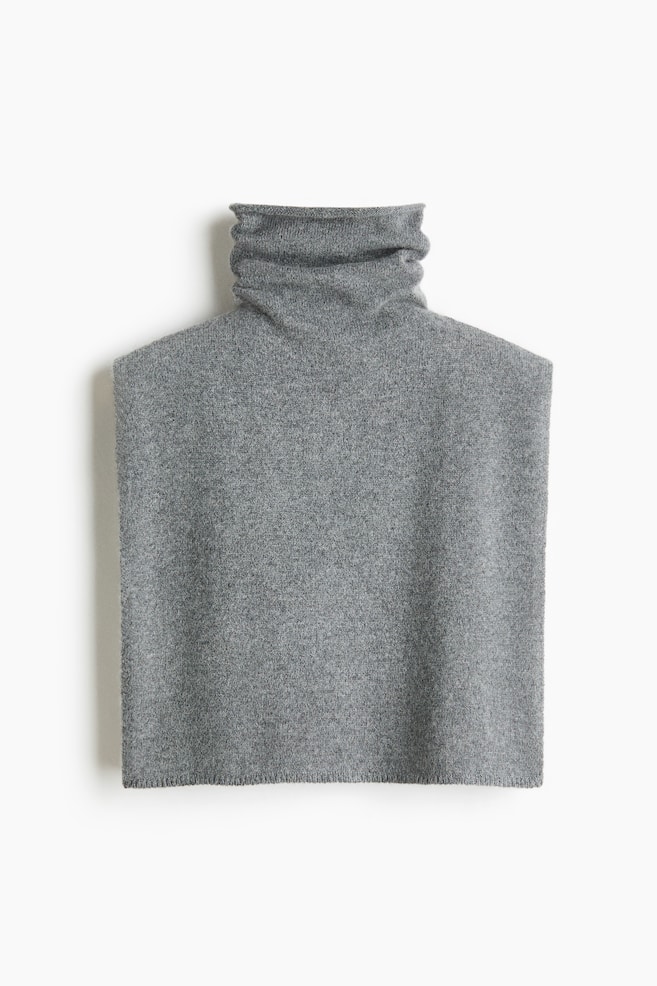 Un col bavette en maille gris chiné est présenté de face, avec un col roulé haut et souple, et un corps rectangulaire sans manches aux épaules droites, ainsi quâun ourlet inférieur subtilement côtelé. - 1