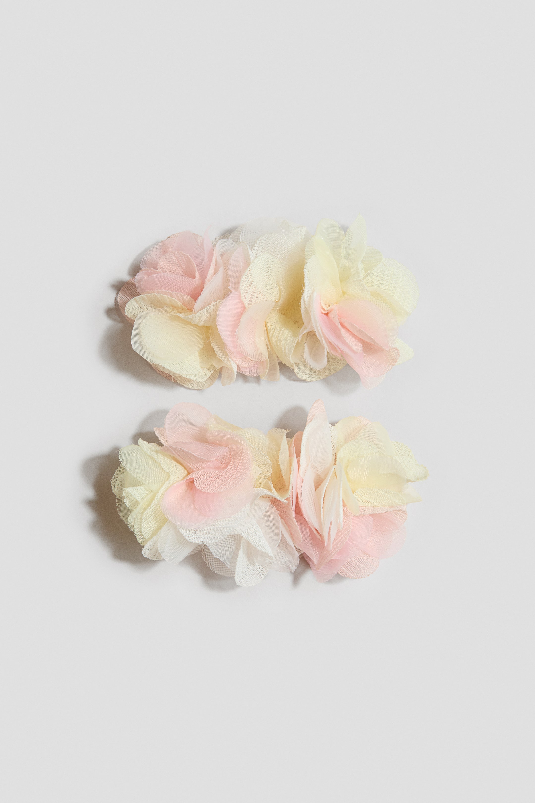 View larger image: Two clusters of fabric flowers feature layered petals in pastel pink, soft yellow, and white. Each cluster is crafted from sheer, ruffled fabric, creating a light and airy texture.