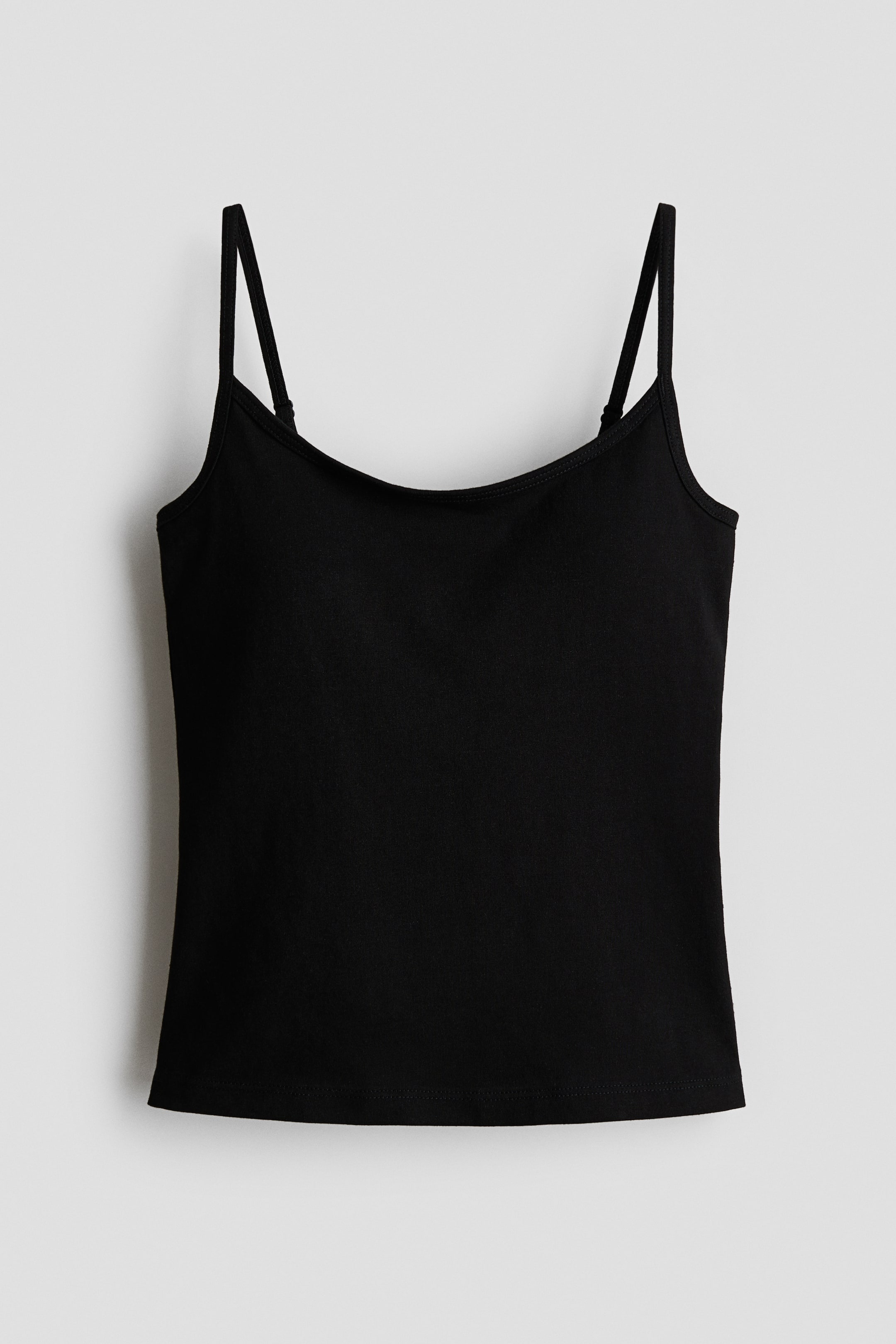 Grösseres Bild ansehen: Ein schwarzes Camisole-Top wird von vorne präsentiert, mit schmalen, verstellbaren Trägern. Es zeigt einen Rundhalsausschnitt und einen geraden Saum in einem glatten Stoff.