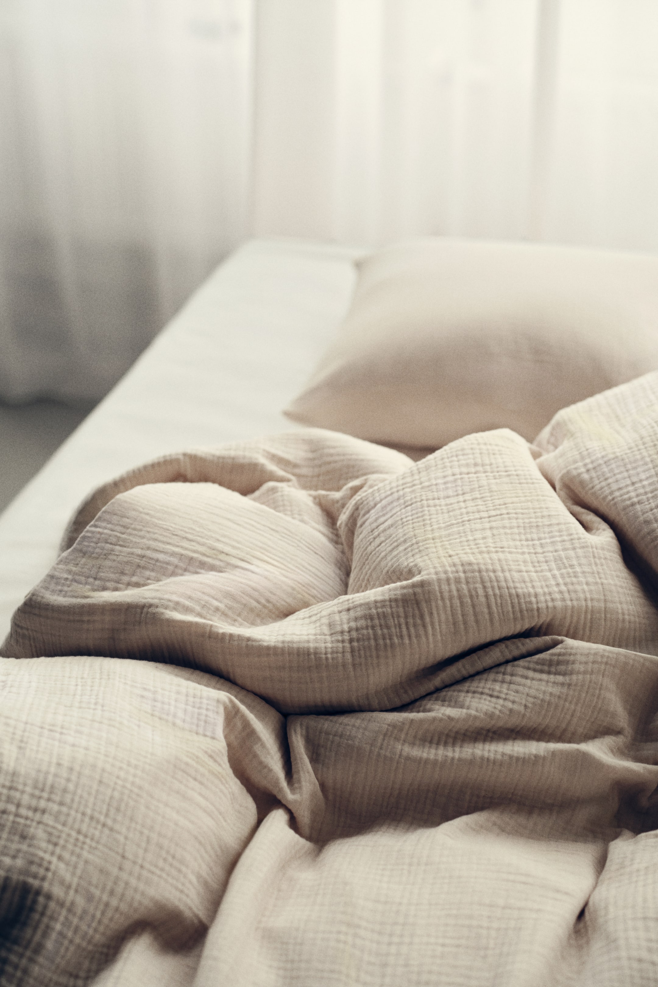 View larger image: A light beige bedding set showcases a crinkled duvet cover and a matching pillowcase. The rumpled duvet cover is positioned on a white sheet, angled from the bottom left to the top right, with the pillowcase visible at the top right.