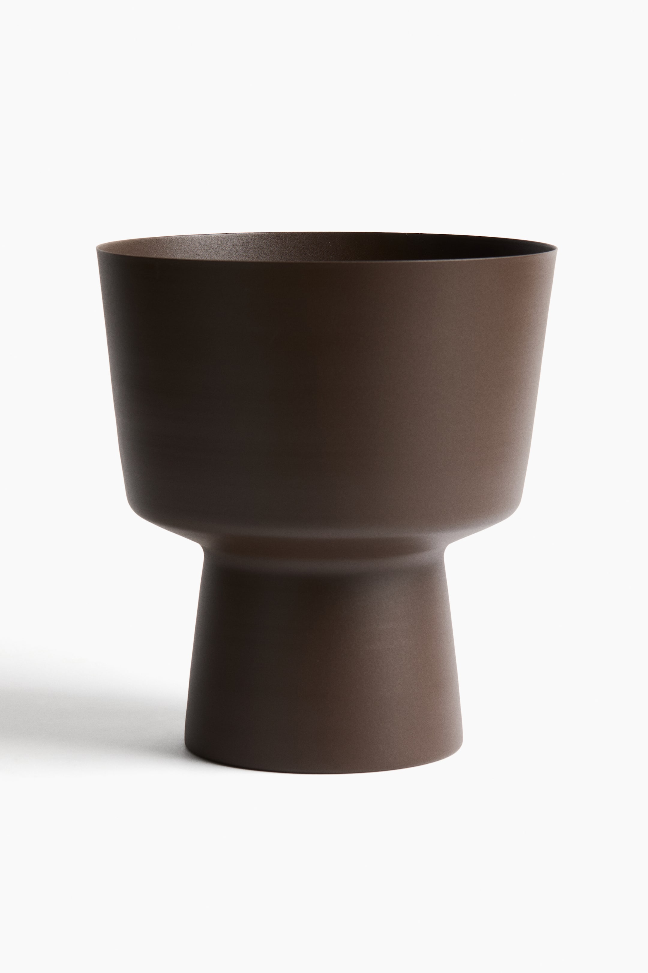 View larger image: A large plant pot in dark-brown painted metal is shown from the front, featuring a wide, slightly flared top section that tapers to a distinct pedestal-like base.