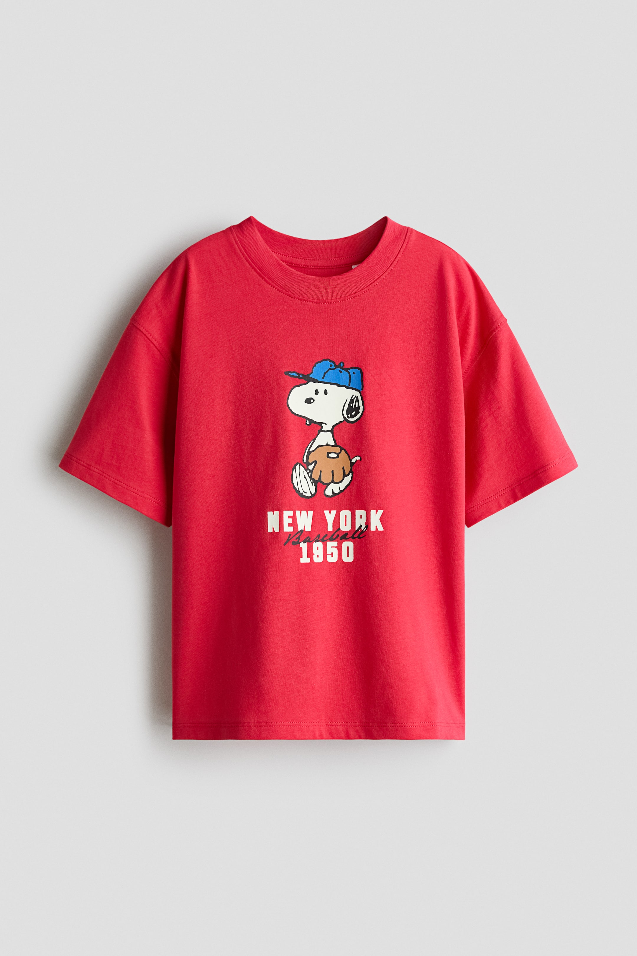 View larger image: A loose-fit red T-shirt in soft cotton jersey is shown from the front, featuring a round, rib-trimmed neckline, dropped shoulders, and a straight-cut hem. A central print motif is depicting a cartoon dog wearing a blue baseball cap and holding a brown baseball glove, with the text 'NEW YORK Baseball 1950' appearing beneath it.