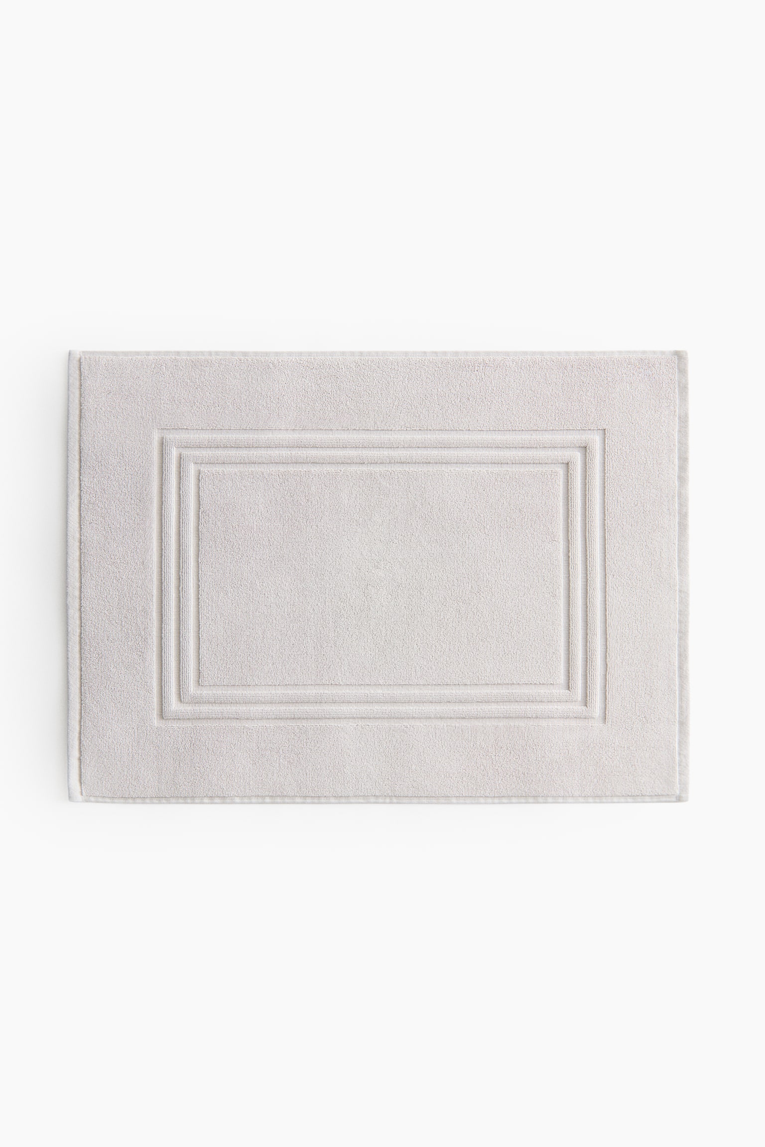 A light grey rectangular mat featuring a textured surface with a raised double-bordered rectangular design in the centre. - 1