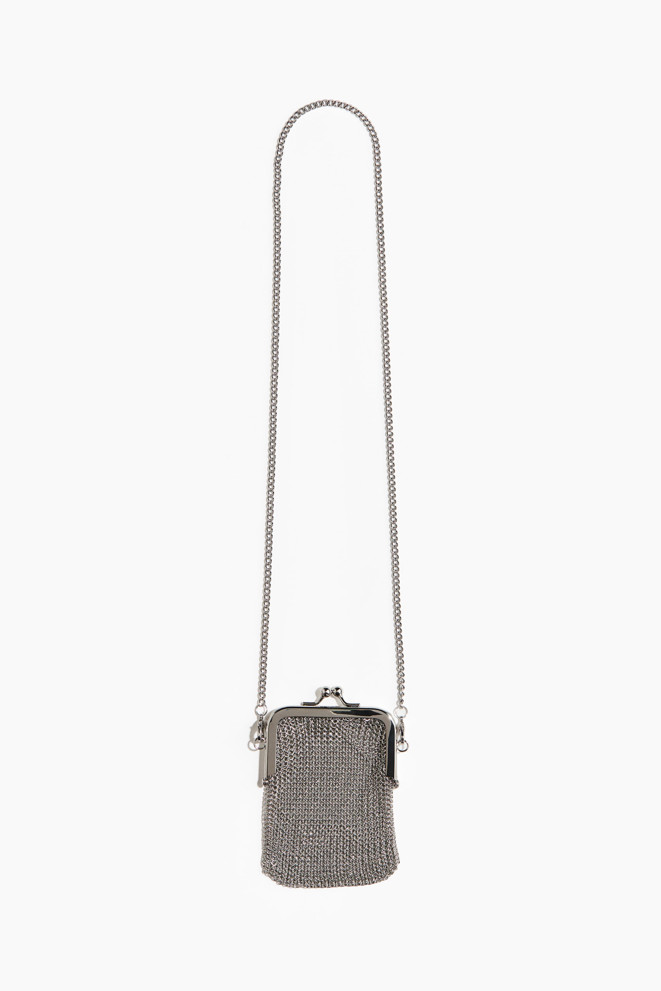 View larger image: A small silver-toned metallic mesh bag hangs, featuring a hinged frame and a kiss-lock clasp at the top. A thin chain strap is attached to the frame, forming a long loop.