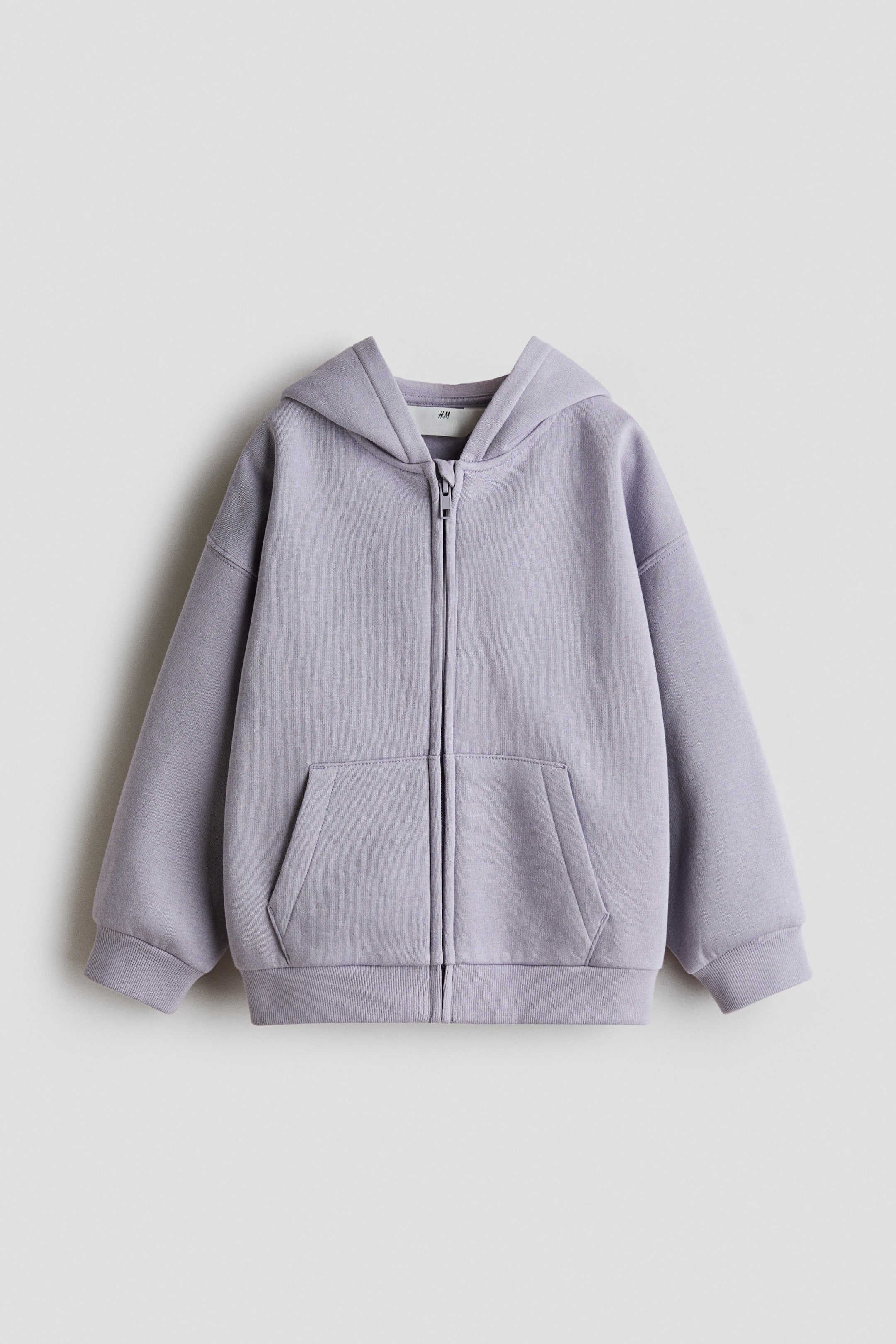 Visualizza immagine più grande: Una felpa con cappuccio color lilla con zip frontale è presentata frontalmente. Presenta un cappuccio, una chiusura con zip centrale, una grande tasca a marsupio, polsini a coste e un orlo a coste.