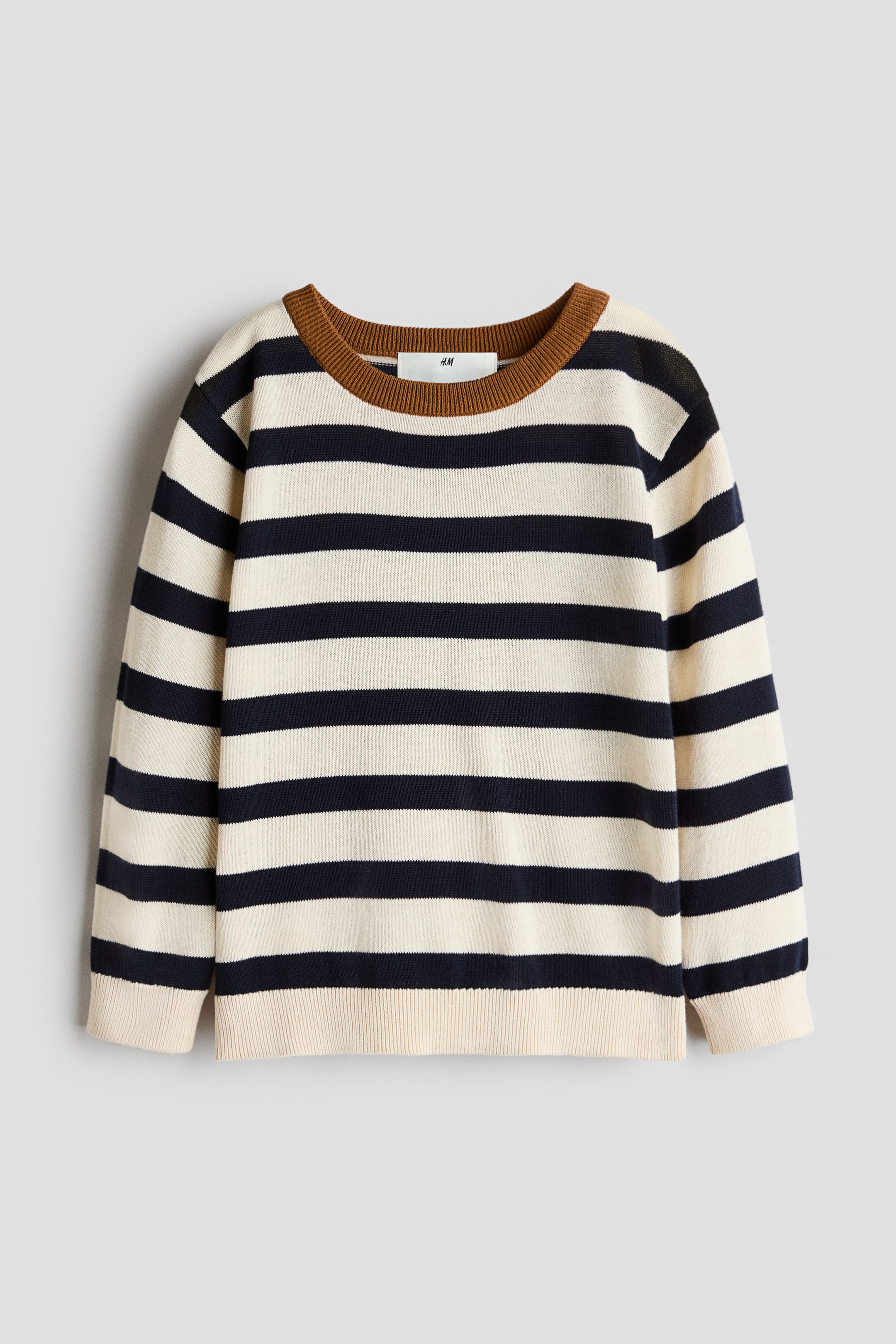 View larger image: A striped sweater is laid flat, front-facing, showcasing off-white and navy blue horizontal stripes. It features a tan ribbed crewneck, long sleeves, and off-white ribbed cuffs and hem.