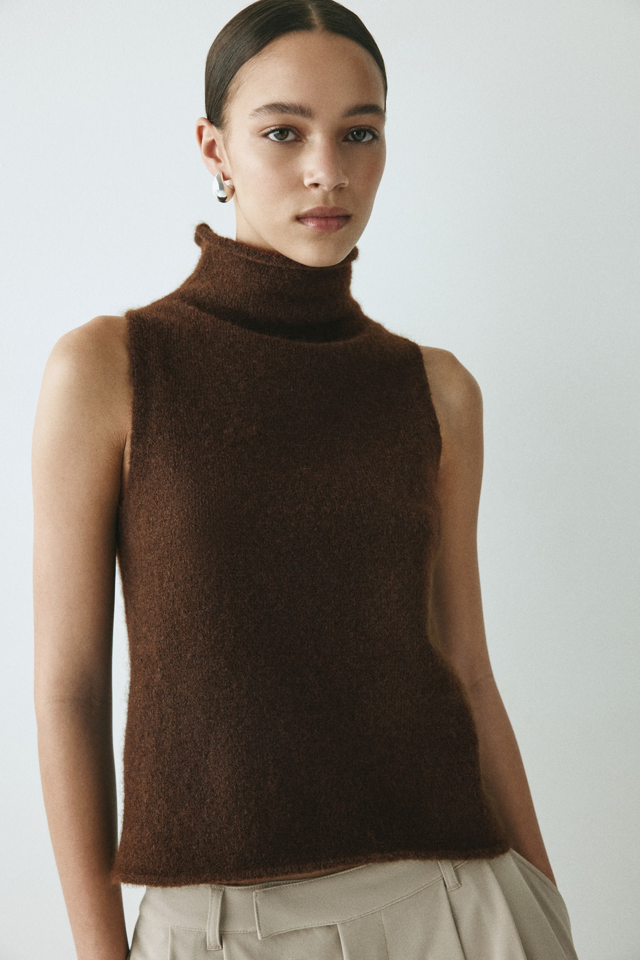 View larger image: A brown sleeveless turtleneck top is pictured. It features a soft, brushed knit texture, a high turtleneck collar, and a straight, sleeveless cut.