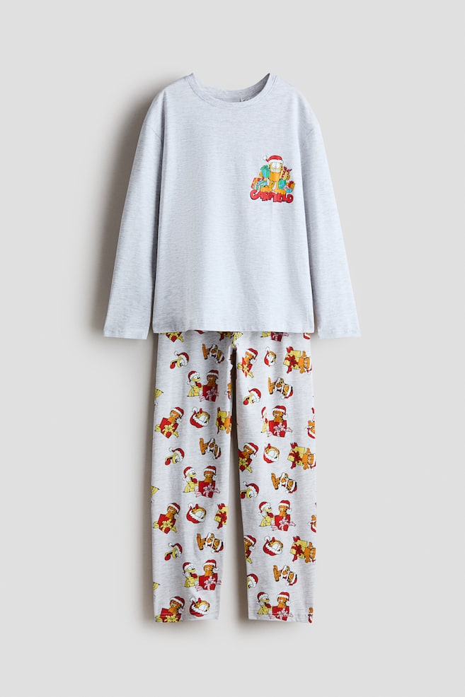 O vedere din faÈÄ a unui set de pijama de culoare gri deschis, format dintr-un tricou cu mÃ¢necÄ lungÄ Èi pantaloni asortaÈi. Tricoul afiÈeazÄ un mic grafic pe piept cu Garfield Èi cadouri de sÄrbÄtori, Ã®n timp ce pantalonii asortaÈi prezintÄ un imprimeu festiv integral cu Garfield Èi Odie. - 1