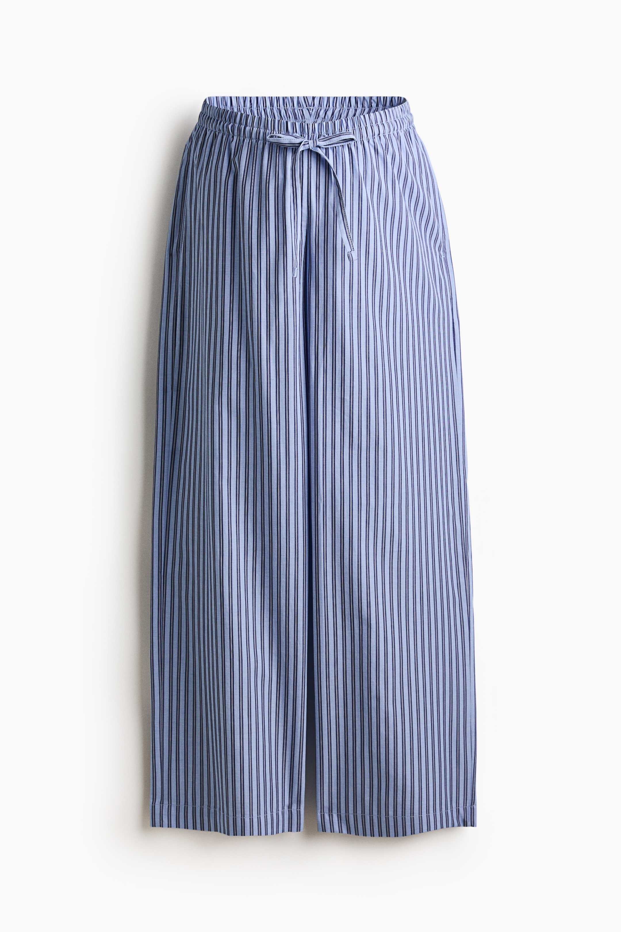 View larger image: The front of the trousers showcases a light blue fabric adorned with thin dark vertical stripes. An elasticized waistband features a drawstring tied in a bow at the front, and the legs present a wide-cut silhouette.