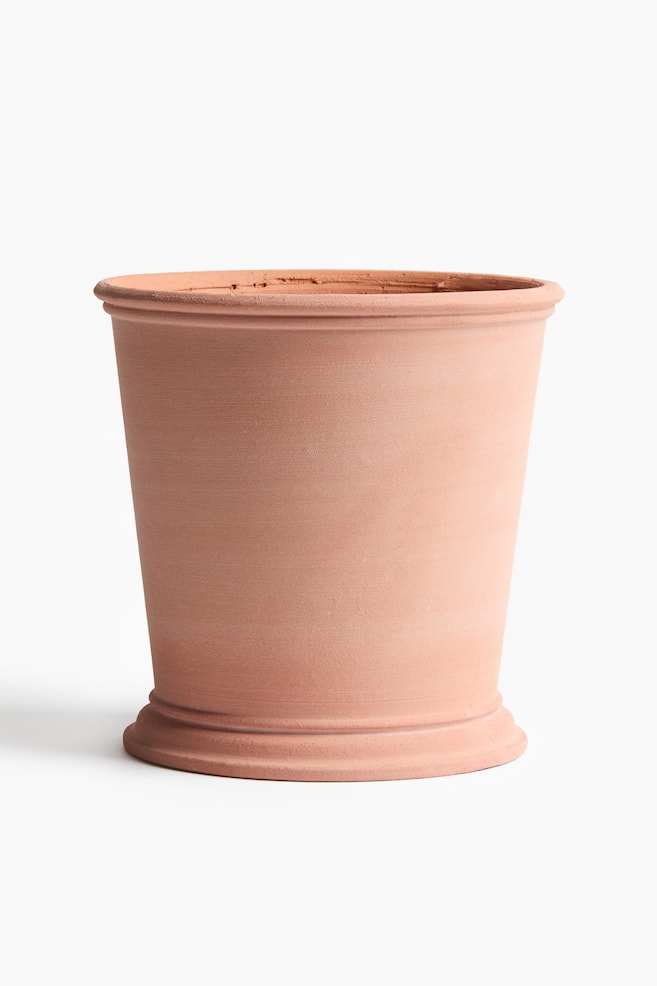 A terracotta pot is shown front-facing. It features a tapered body, a rolled rim at the top, and a flared, ridged base. - 1