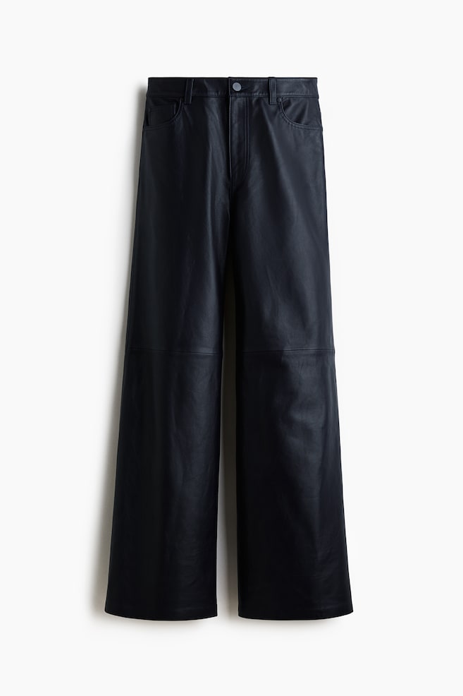 Black wide-leg leather-look pants are being displayed from the front. They are featuring a button closure, belt loops, two front slash pockets with a small coin pocket, and horizontal seam lines across the thighs. - 1