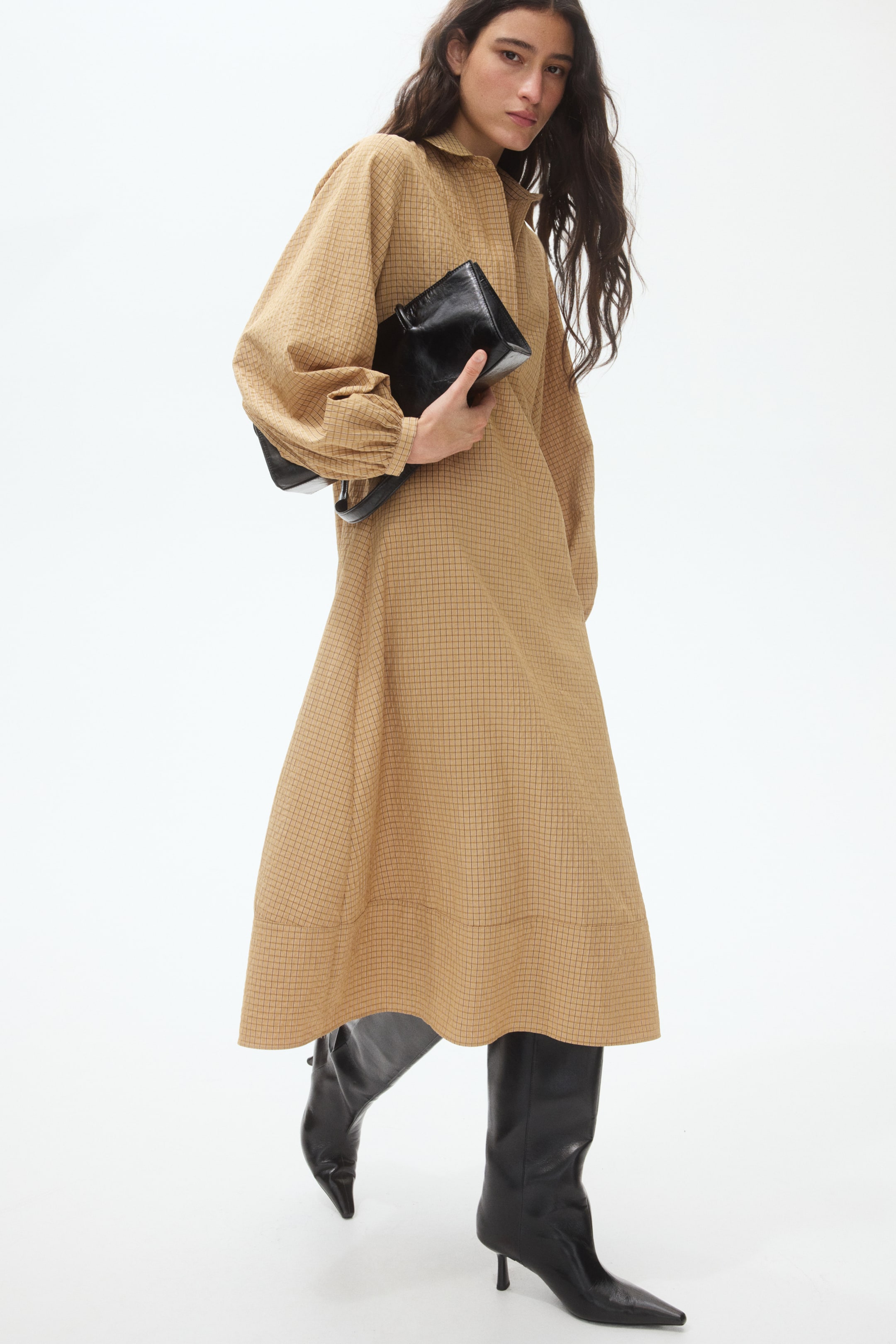 View larger image: The dress is a tan midi-length garment featuring a subtle grid pattern. It is designed with a pointed collar, voluminous long sleeves gathered into buttoned cuffs, and a flowing A-line skirt.