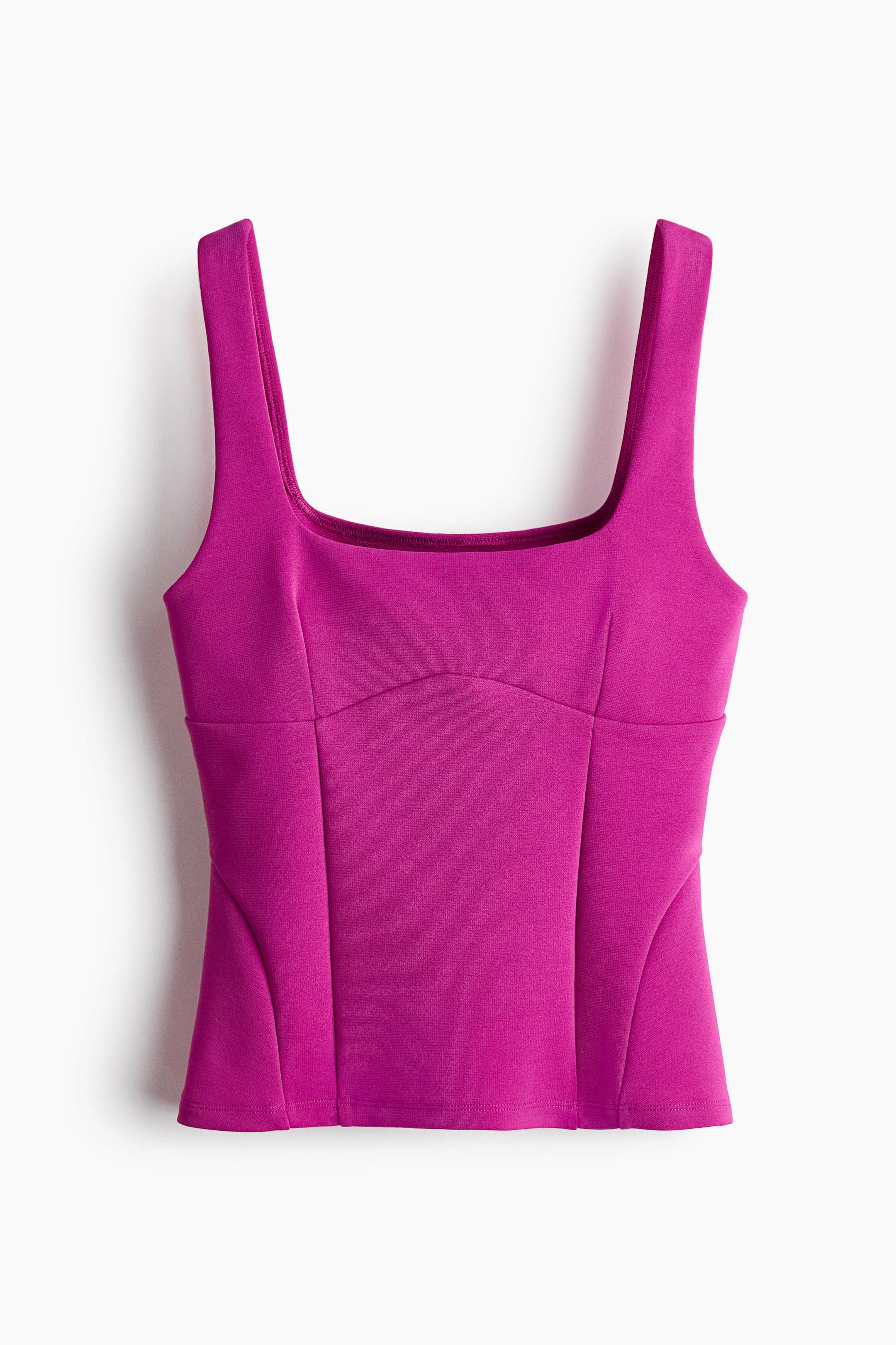 View larger image: A fitted magenta top in heavy interlock jersey is shown from the front, featuring a square neckline and wide shoulder straps. The design is constructed with prominent visible seams across the bodice and inset panels at the hem, creating a structured peplum silhouette.