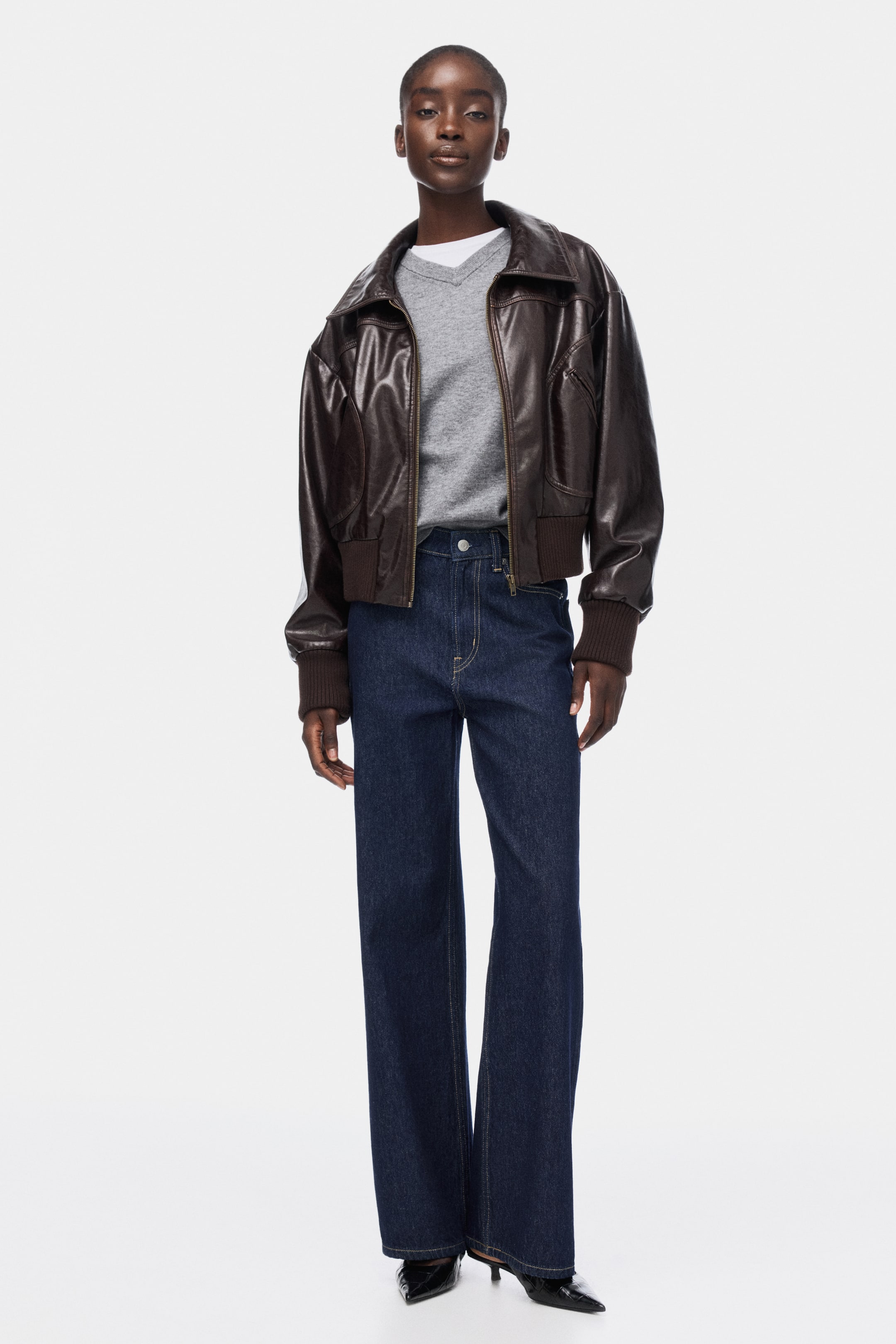 Agrandir l'image: Les jeans à délavage foncé présentent une silhouette taille haute à jambes larges vue de face, avec des surpiqûres contrastantes jaune-or et une fermeture à bouton unique.